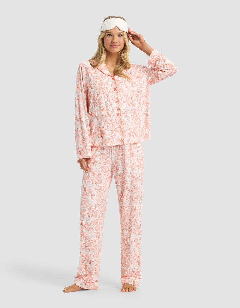 A woman smiles barefoot in Cozy Earth Women's Bamboo Stretch-Knit Pajama Pant with a white sleep mask pushed up on her forehead, standing against a plain light background.
