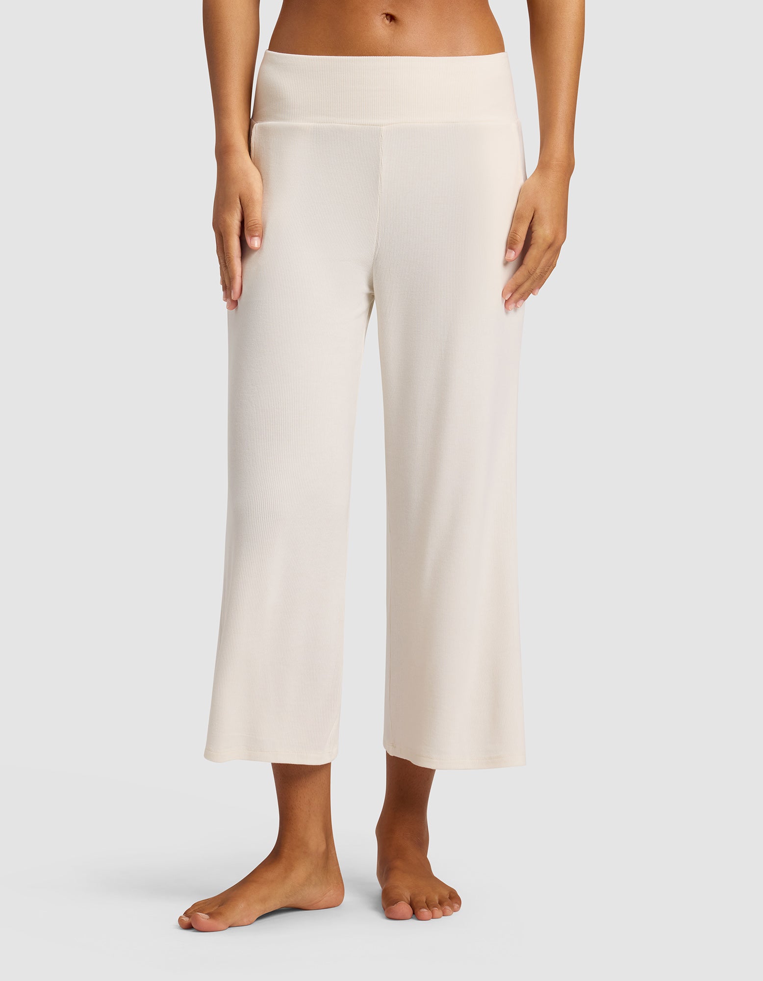 A woman stands barefoot against a plain backdrop wearing Cozy Earth’s Women’s Bamboo Rib-Knit Lounge Capri in Ivory, featuring wide-leg, cropped design, high waistband, and relaxed fit.|Color:Ivory