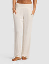 A woman models Cozy Earth’s Women’s Bamboo Rib-Knit Lounge Pant in cream, featuring an elastic waistband and side pockets, standing barefoot against a plain light background.|Color:Ivory