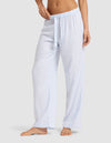A woman stands barefoot in Cozy Earth Women's Soft Woven Pajama Pant, featuring light blue and white vertical stripes, an elastic waistband, and a drawstring, against a plain light gray background. |Color:Spring Blue Stripe