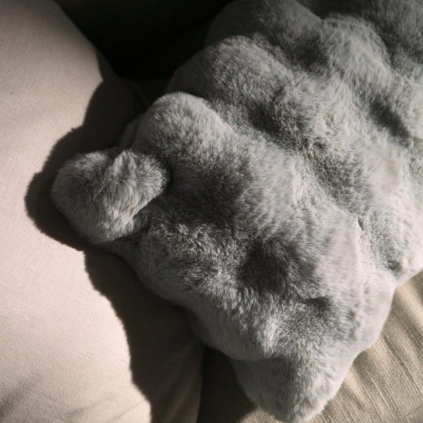 Gray plush pillow on a textured surface