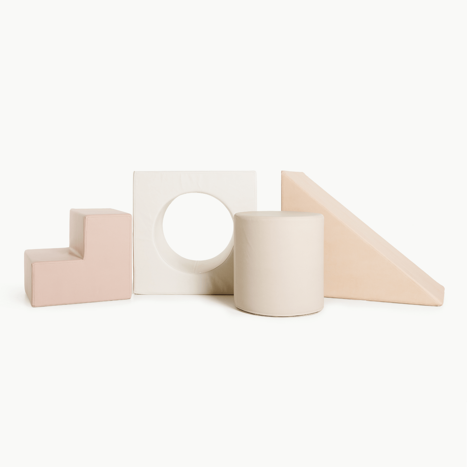 The Gathre Wholesale Block Playset in Tulle features four soft play shapes—an L-block, a square with a circular hole, a cylinder, and a wedge—arranged side by side on a plain white background.