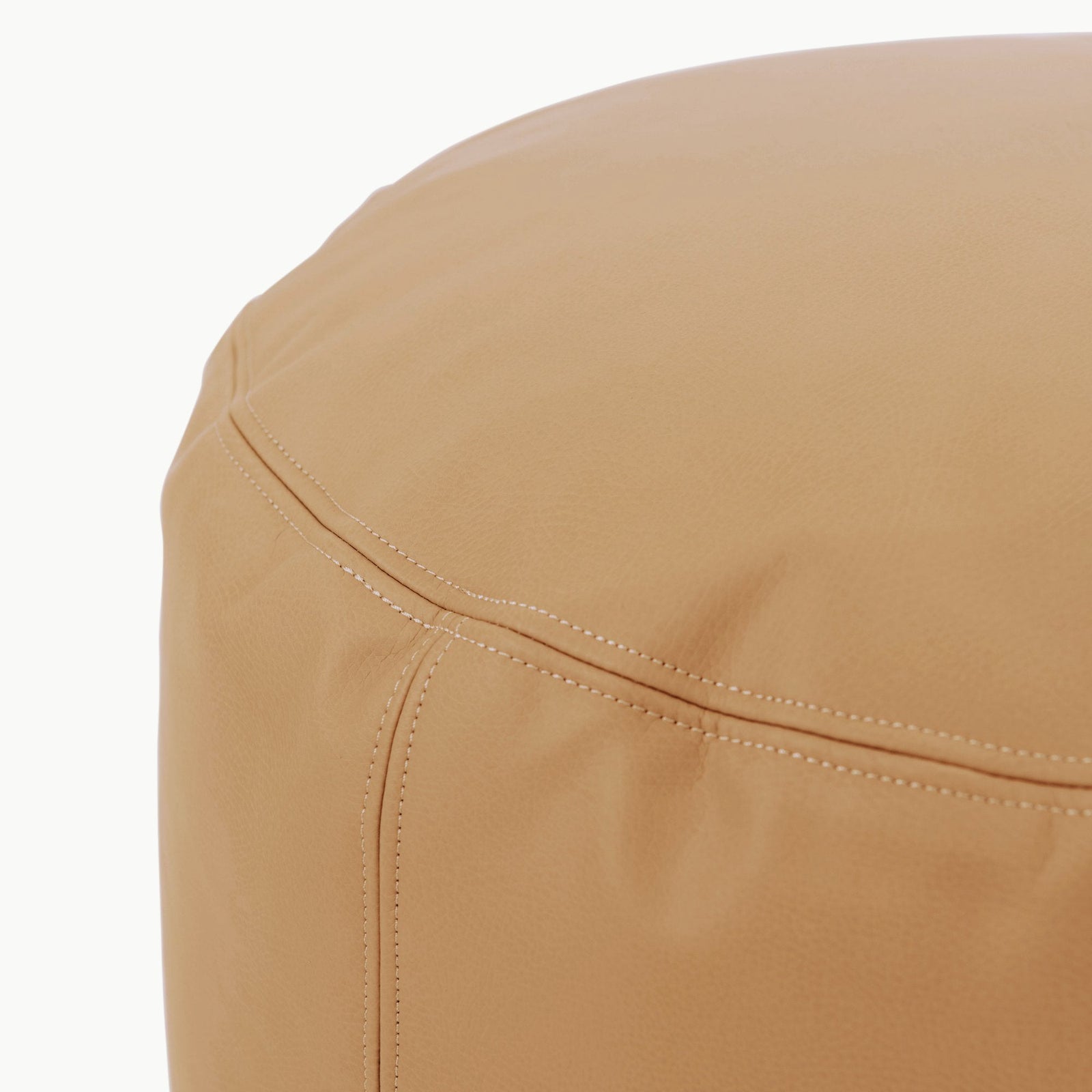 Close-up of the Wholesale Pouf by Gathre, featuring tan leather with visible seams and detailed stitching on its smooth surface.