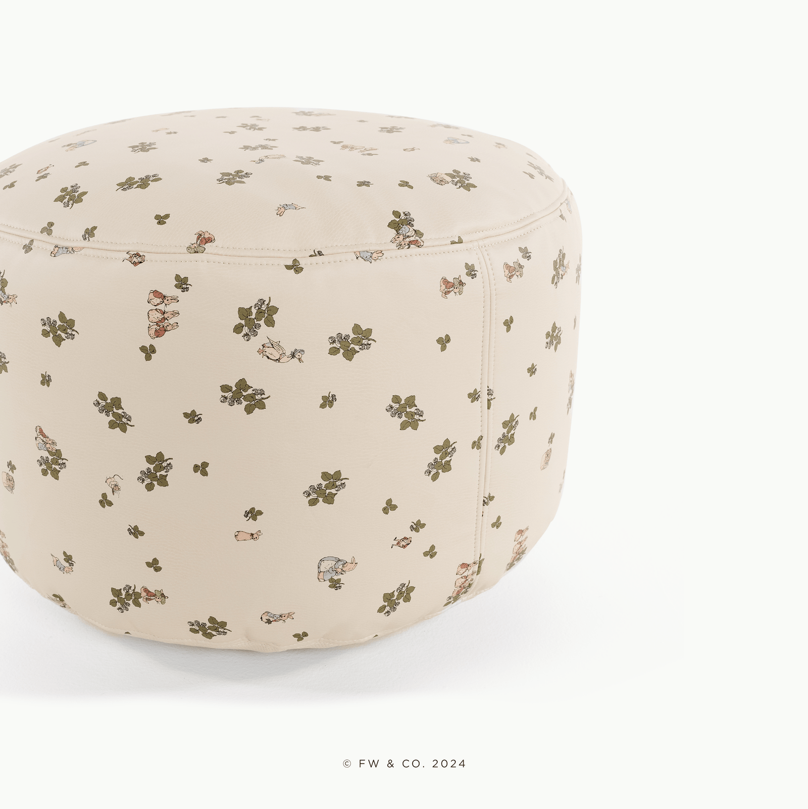 A round, beige Gathre Wholesale Pouf with a subtle green leaf and tiny animal pattern sits on a white surface. Text at the bottom reads "© FW & CO. 2024.