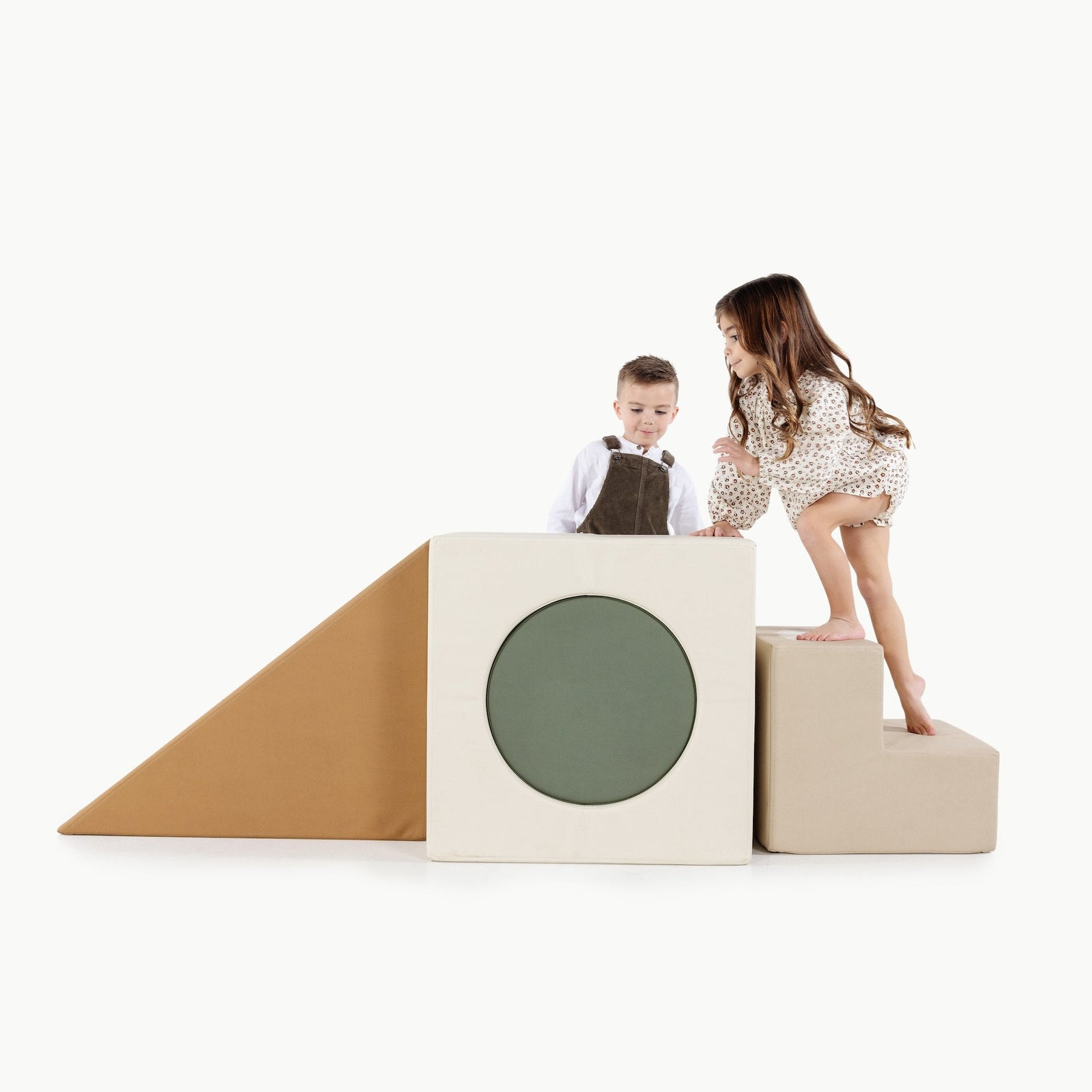 Two children play on the Gathre Wholesale Block Playset, a minimalist foam set featuring geometric shapes like a ramp, a block with a green circle, and a cube, all set against a plain white background.