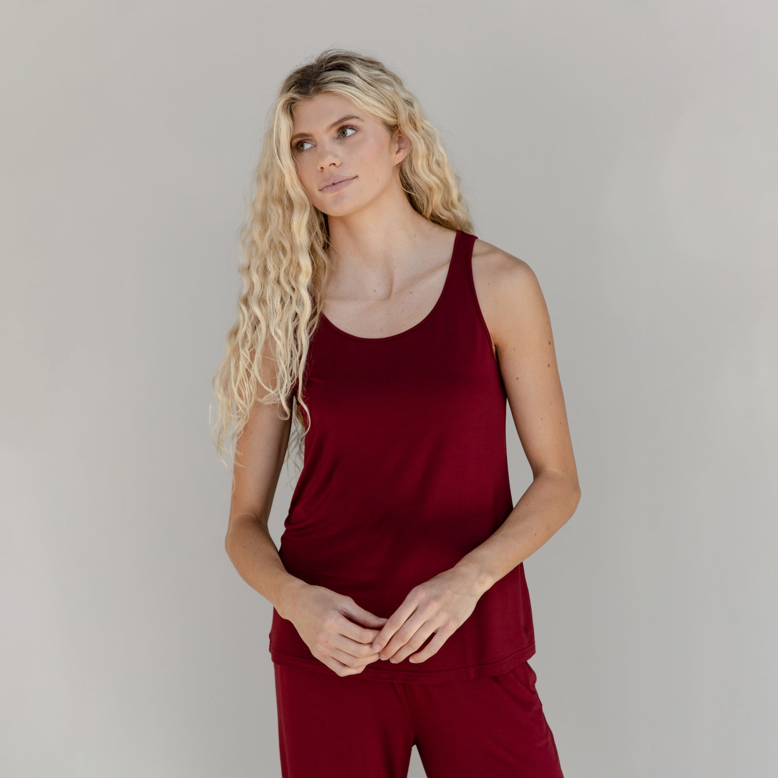 A woman shown from the thighs up wears a red Cozy Earth Stretch Knit Tank
