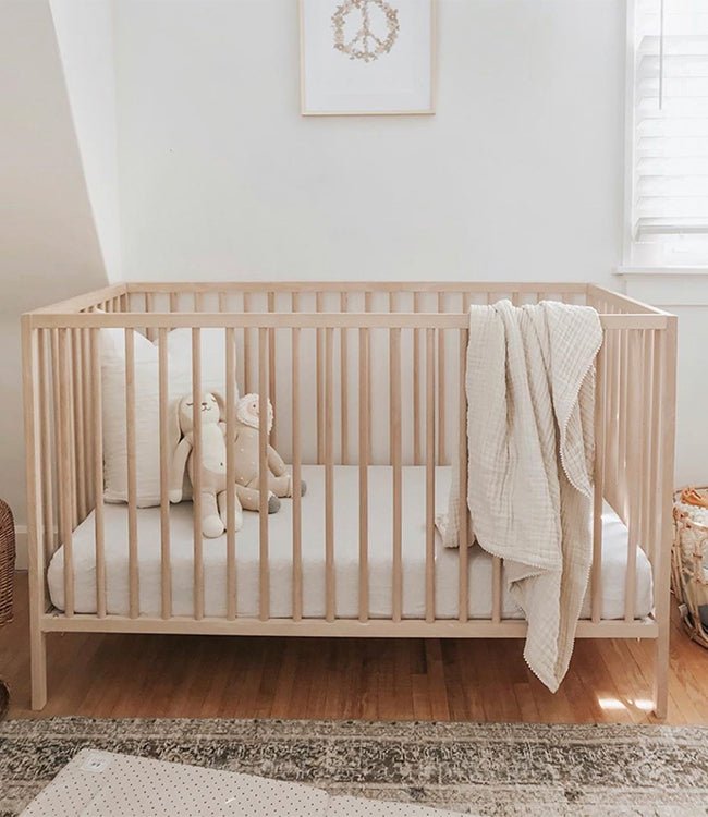 Wooden crib with white sheet in nursery 