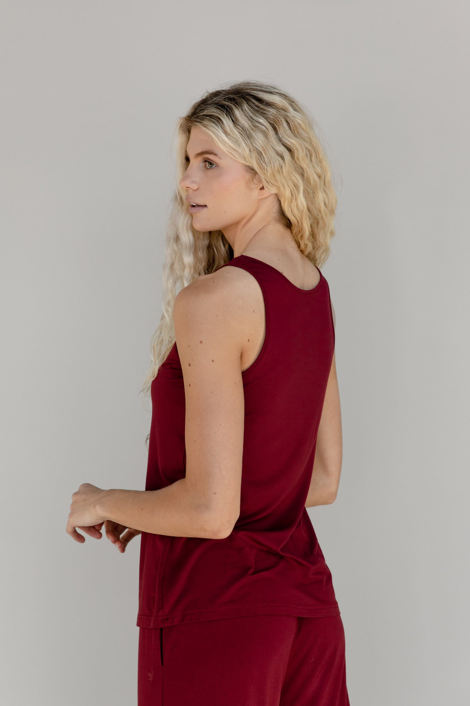 A woman facing to the side wears a red Cozy Earth Stretch Knit Tank