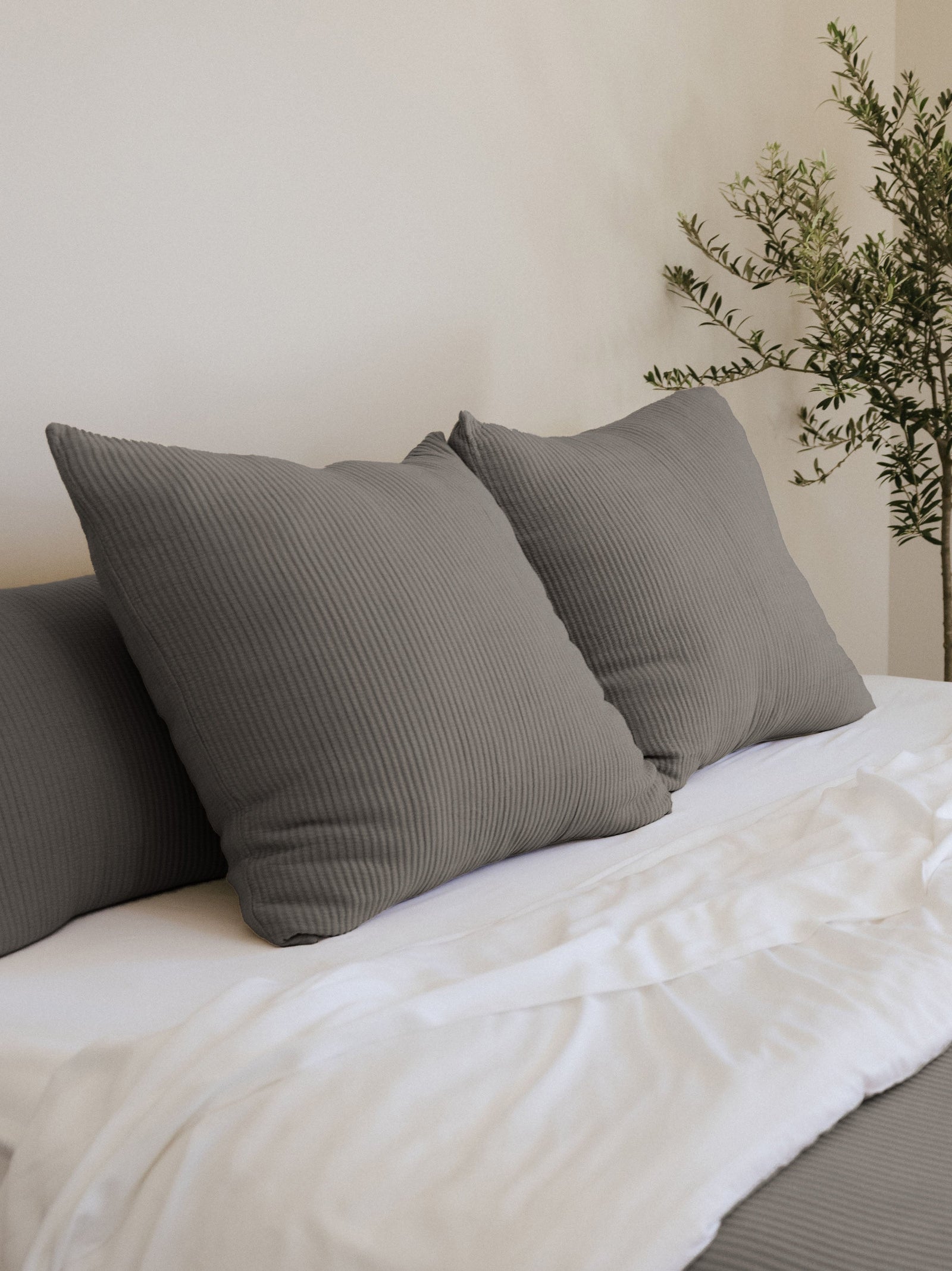 Charcoal coverlet shams on a white bed