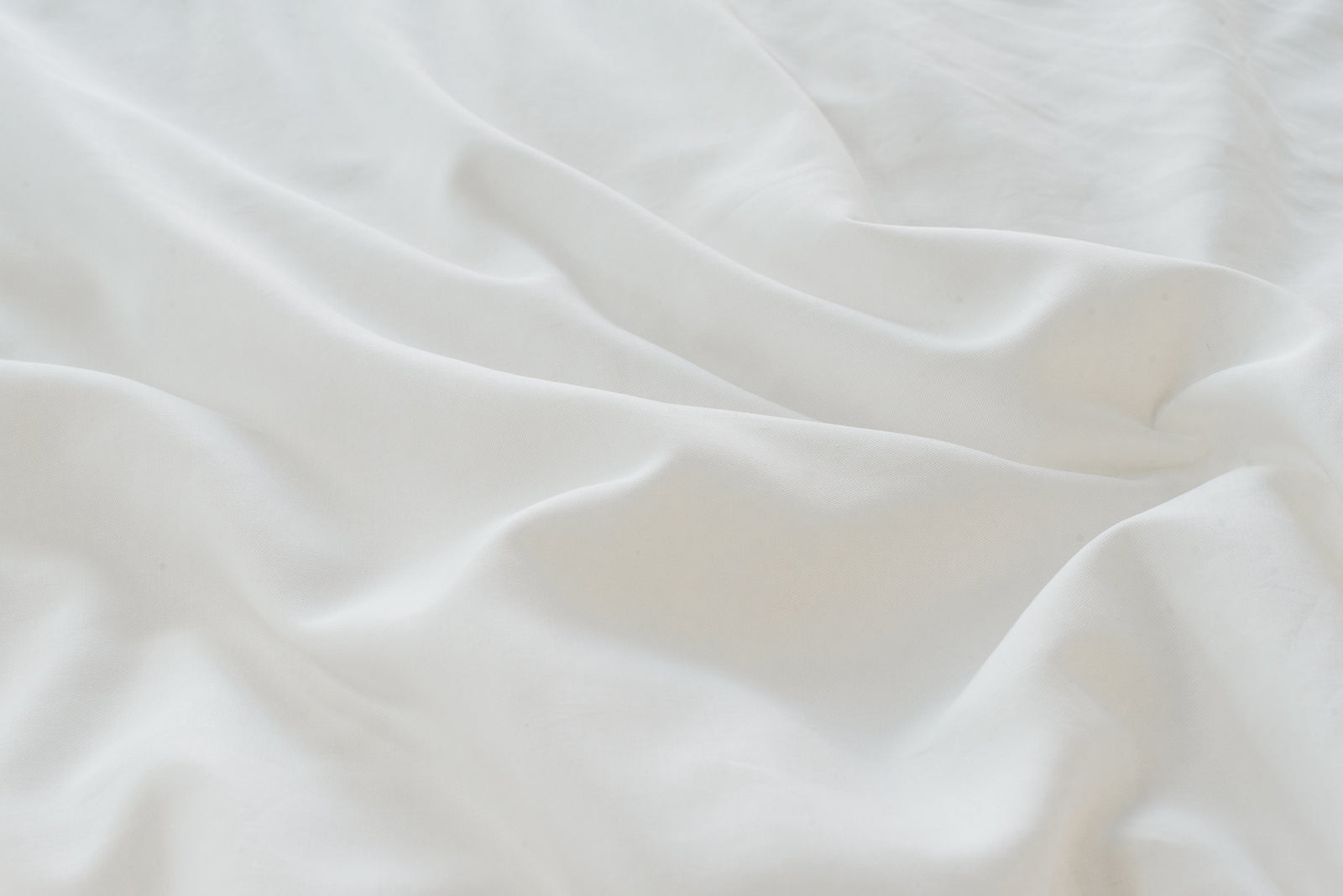 White Linen Bamboo Duvet Cover and comforter resting on a bed. Photo or product taken close up.