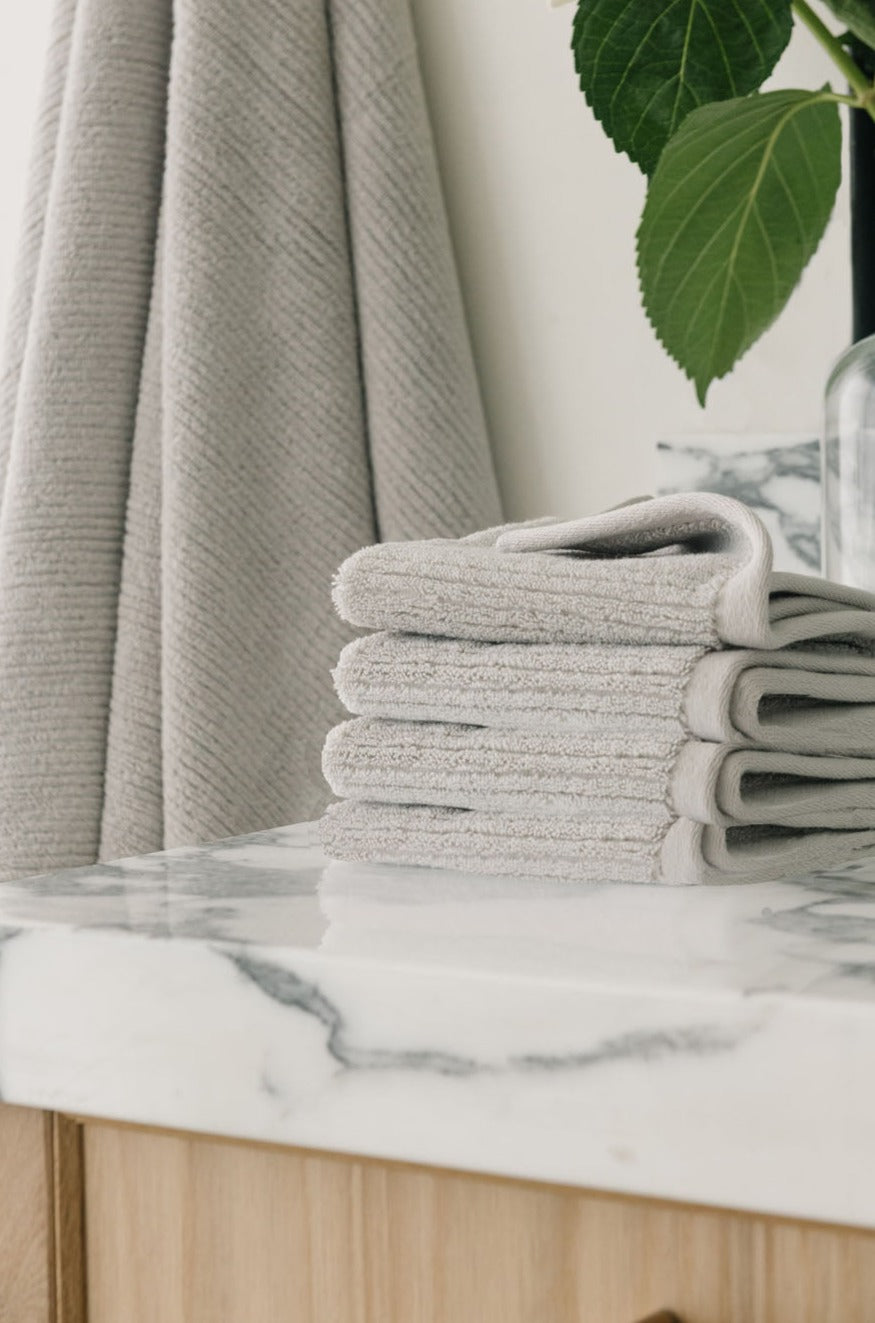Ribbed Terry Wash Cloths in the color Light Grey. Photo of product taken on a white marble sink.