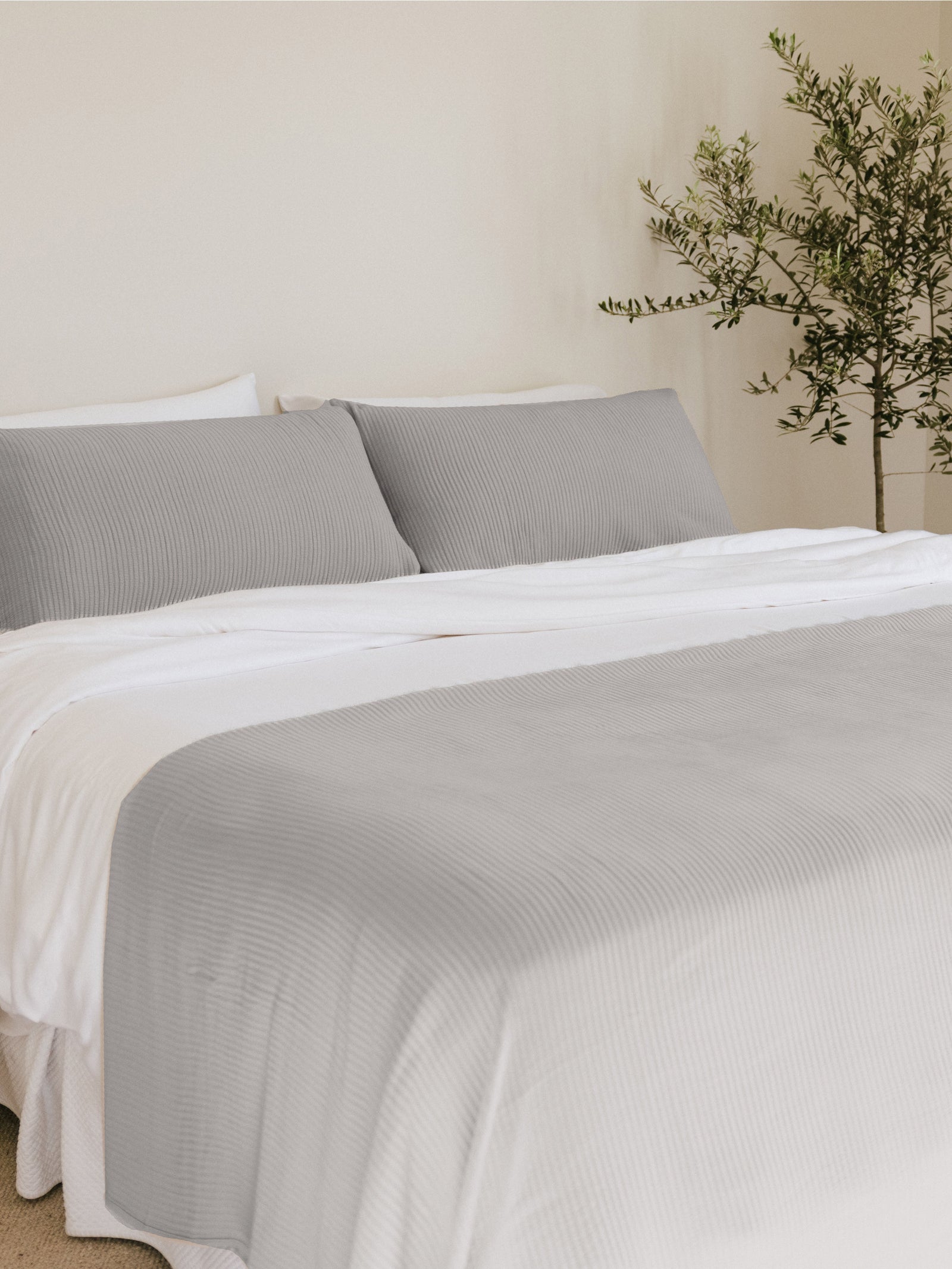 Light Grey coverlet and shams on a bed 