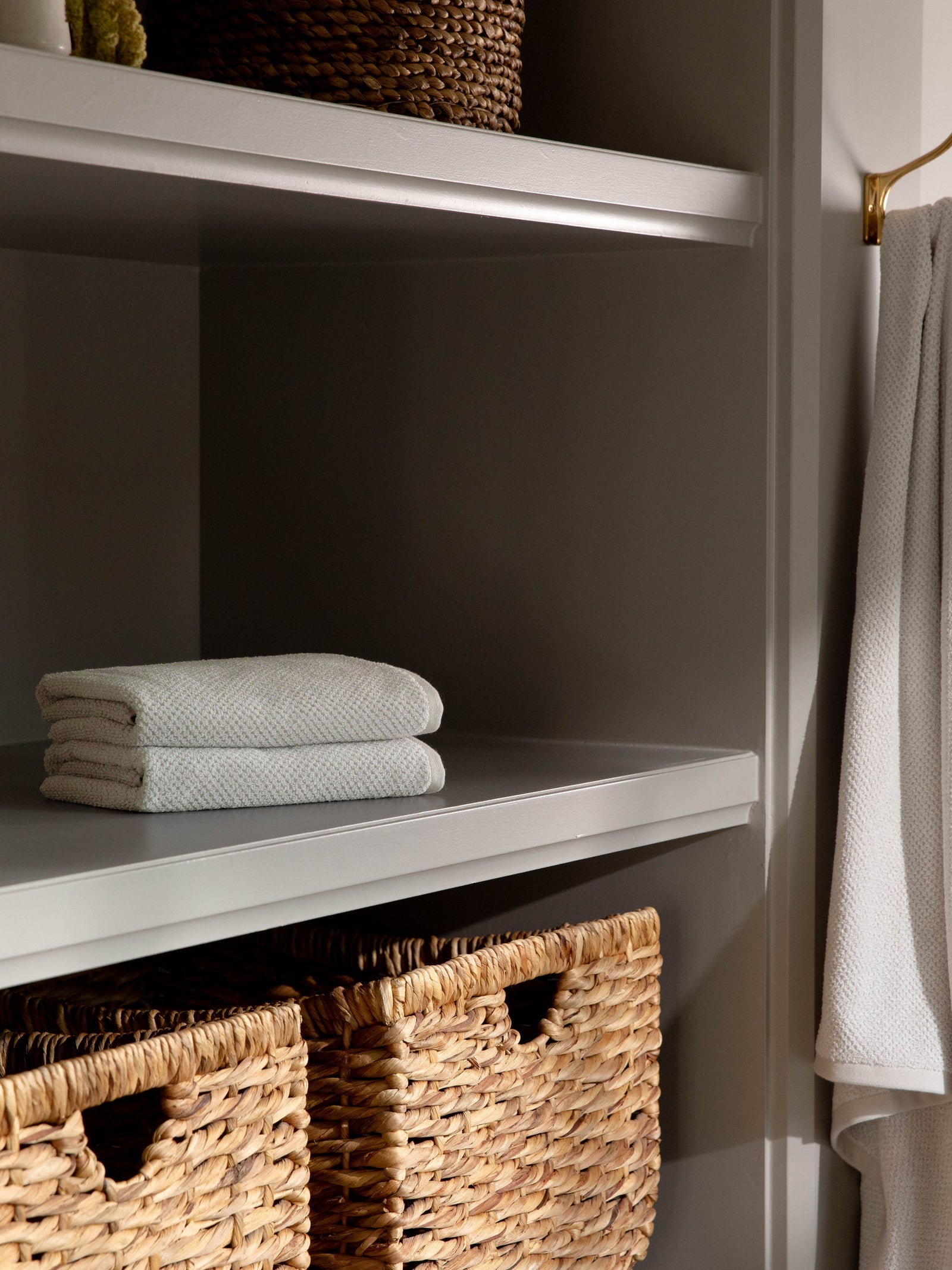Nantucket Hand Towels in the color Heathered Light Grey. Photo of Nantucket Hand Towels taken with the hand towels resting on a shelf in a bathroom.