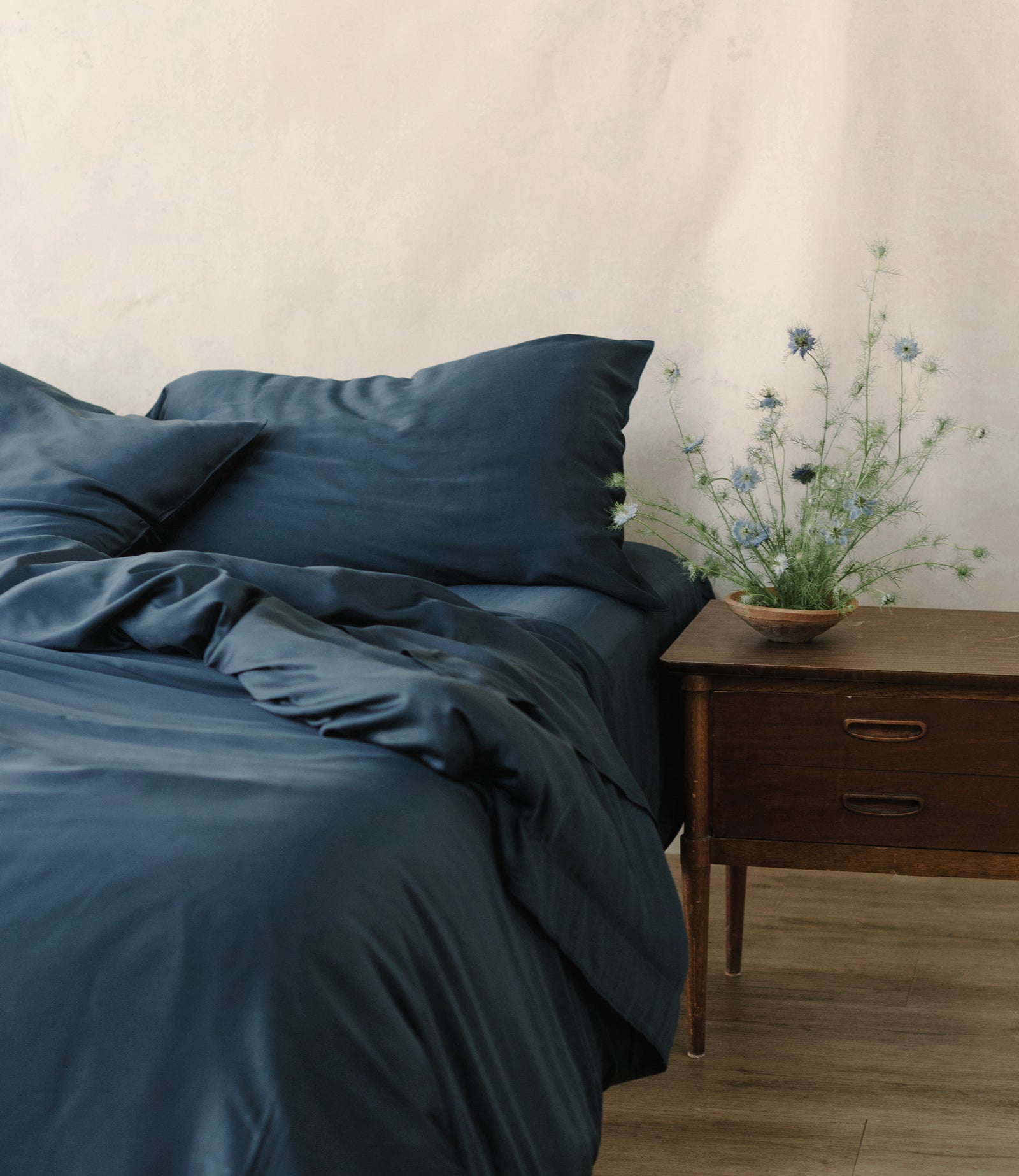 Unmade bed with navy bedding 
