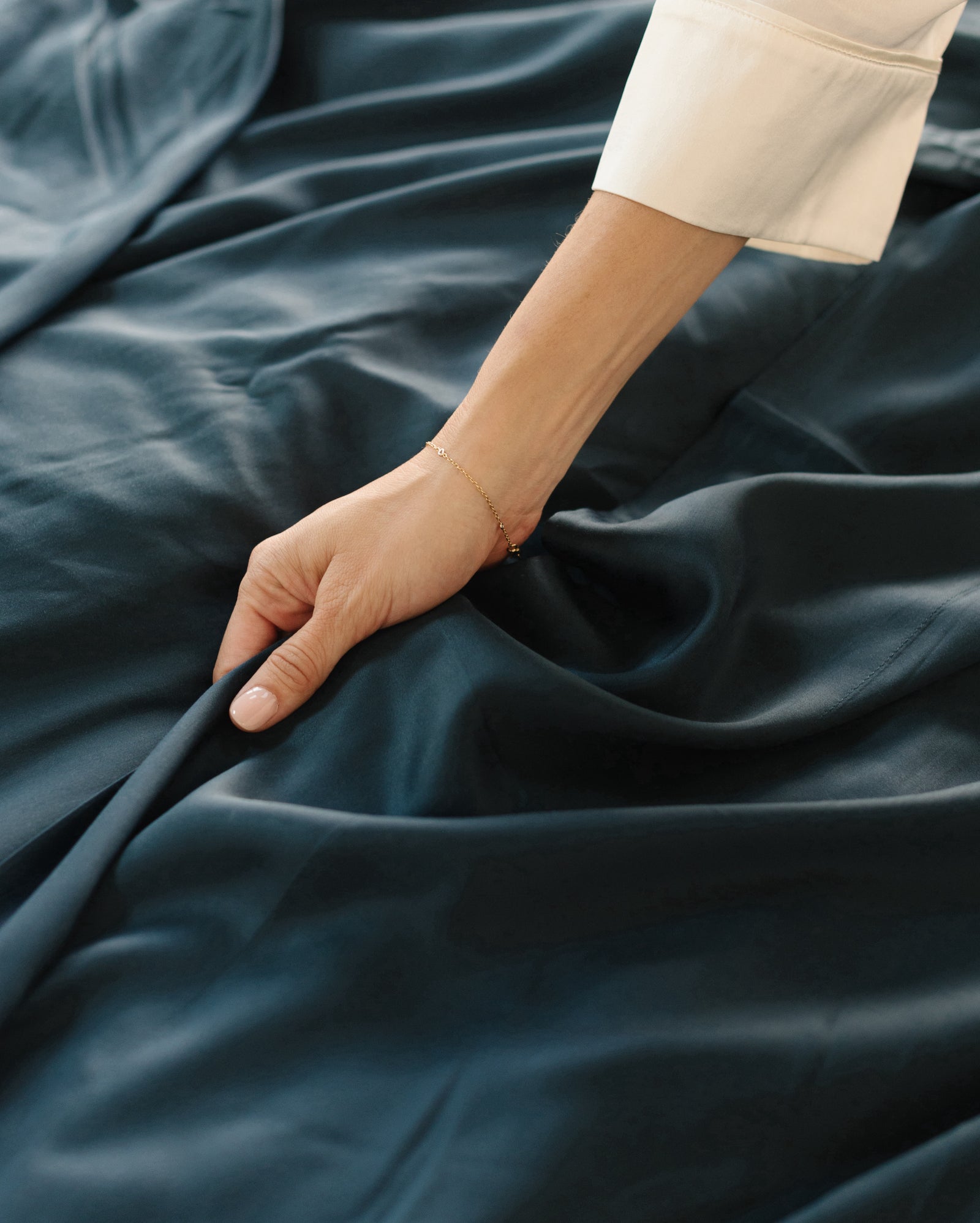Close up of arm reaching out touching navy bedding 