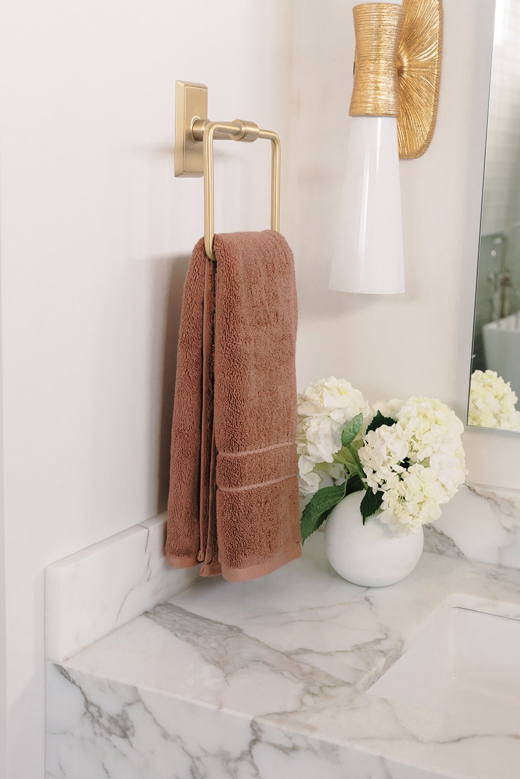 Premium Plush Hand Towel in the color Clay. Photo of Clay Premium Plush Hand Towel taken in a bathroom hanging from a gold hand towel ring