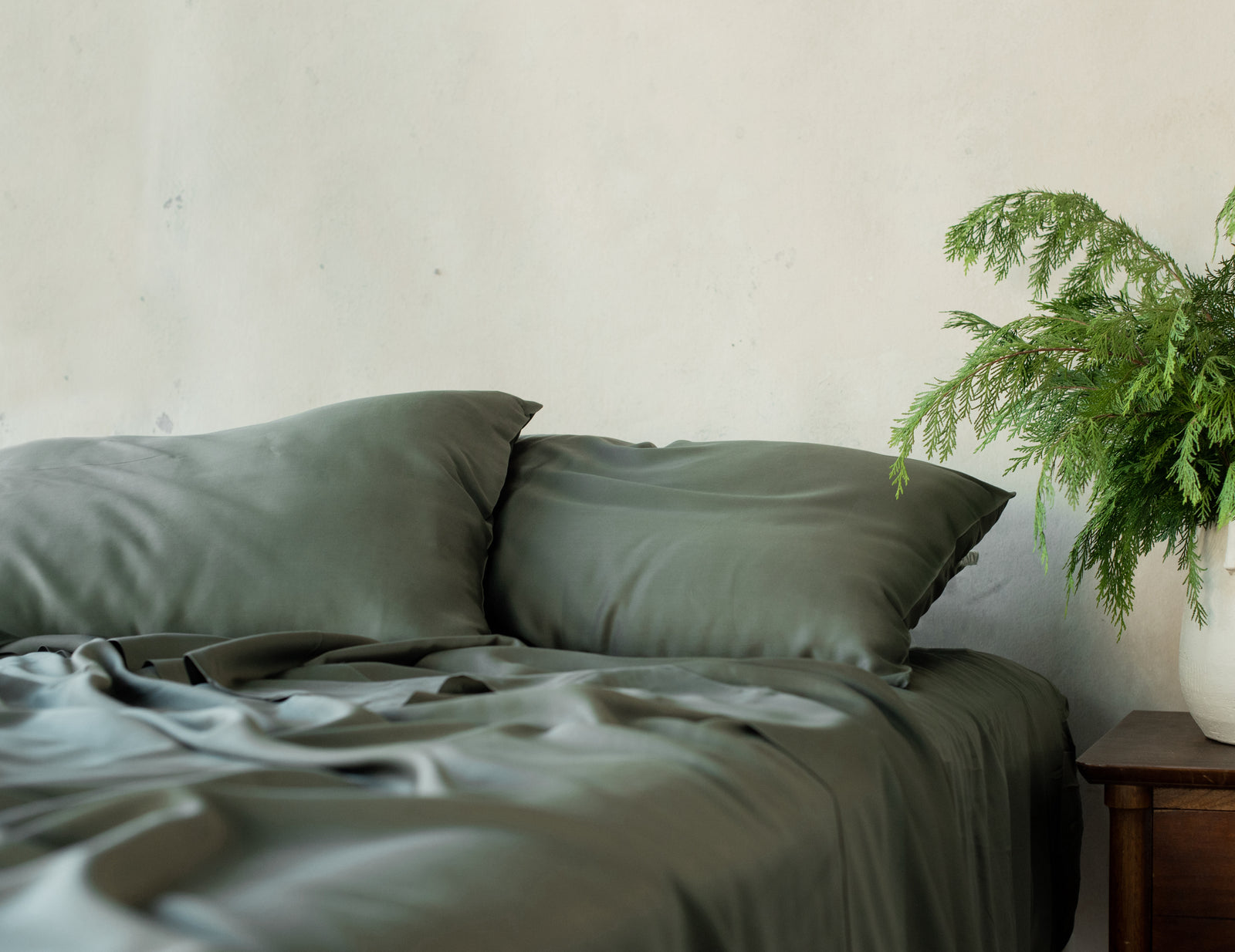 Bed with olive bedding and a plant on the nightstand standard/king/body