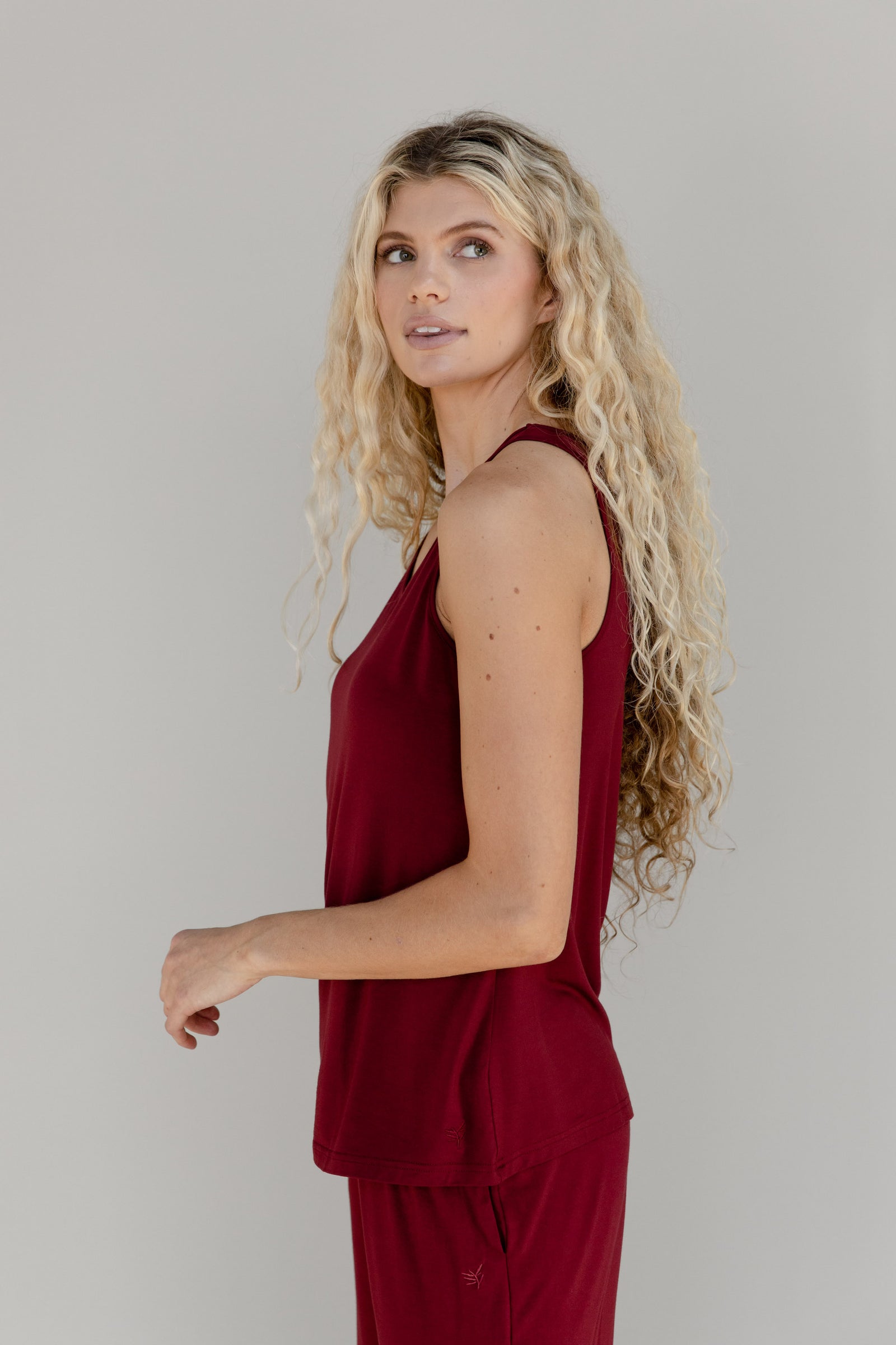 A woman shown from the thighs up wears a red Cozy Earth Stretch Knit Tank