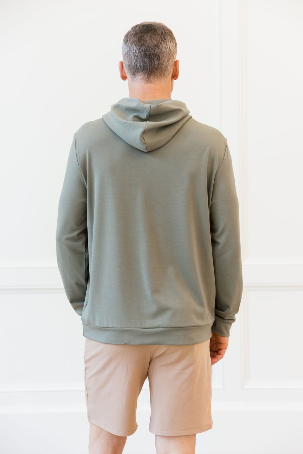 Moss Bamboo Hoodie worn by a man with his back facing the camera. The man is standing in front of white background.