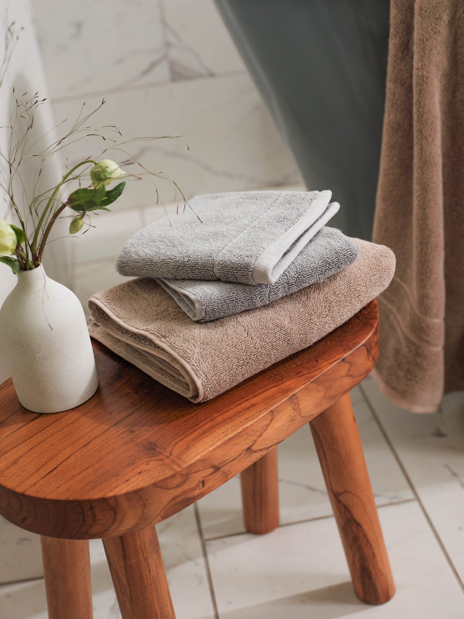 Premium Plush bath towel and wash cloth in the color Sand and Harbor Mist. Photo of Sand, Harbor Mist Premium Plush items taken on stool in a bathroom.