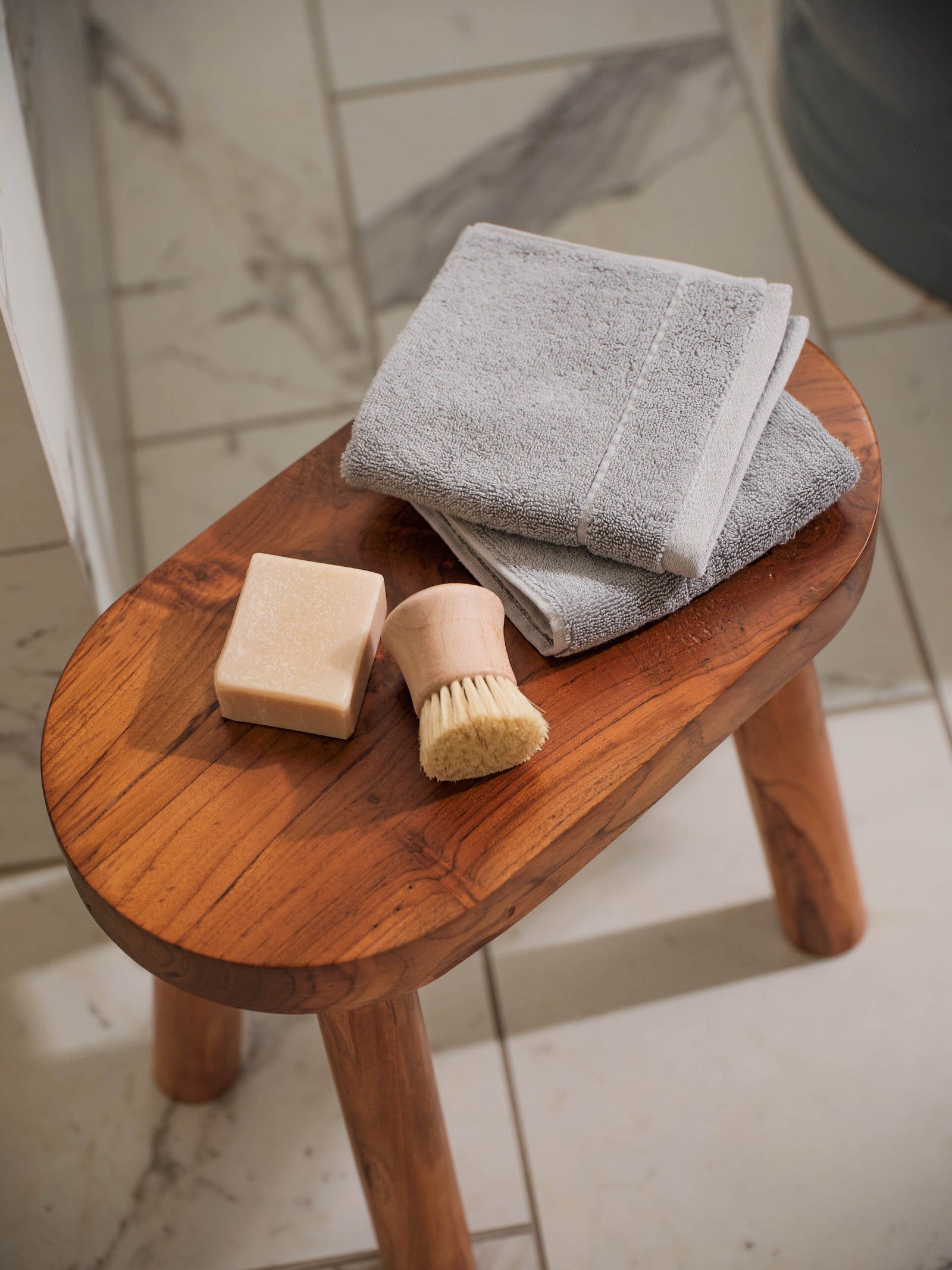 Premium Plush Hand Towels in the color Harbor Mist. Photo of Harbor Mist Premium Plush Hand Towels taken resting on a stool in a bathroom with marble tile.