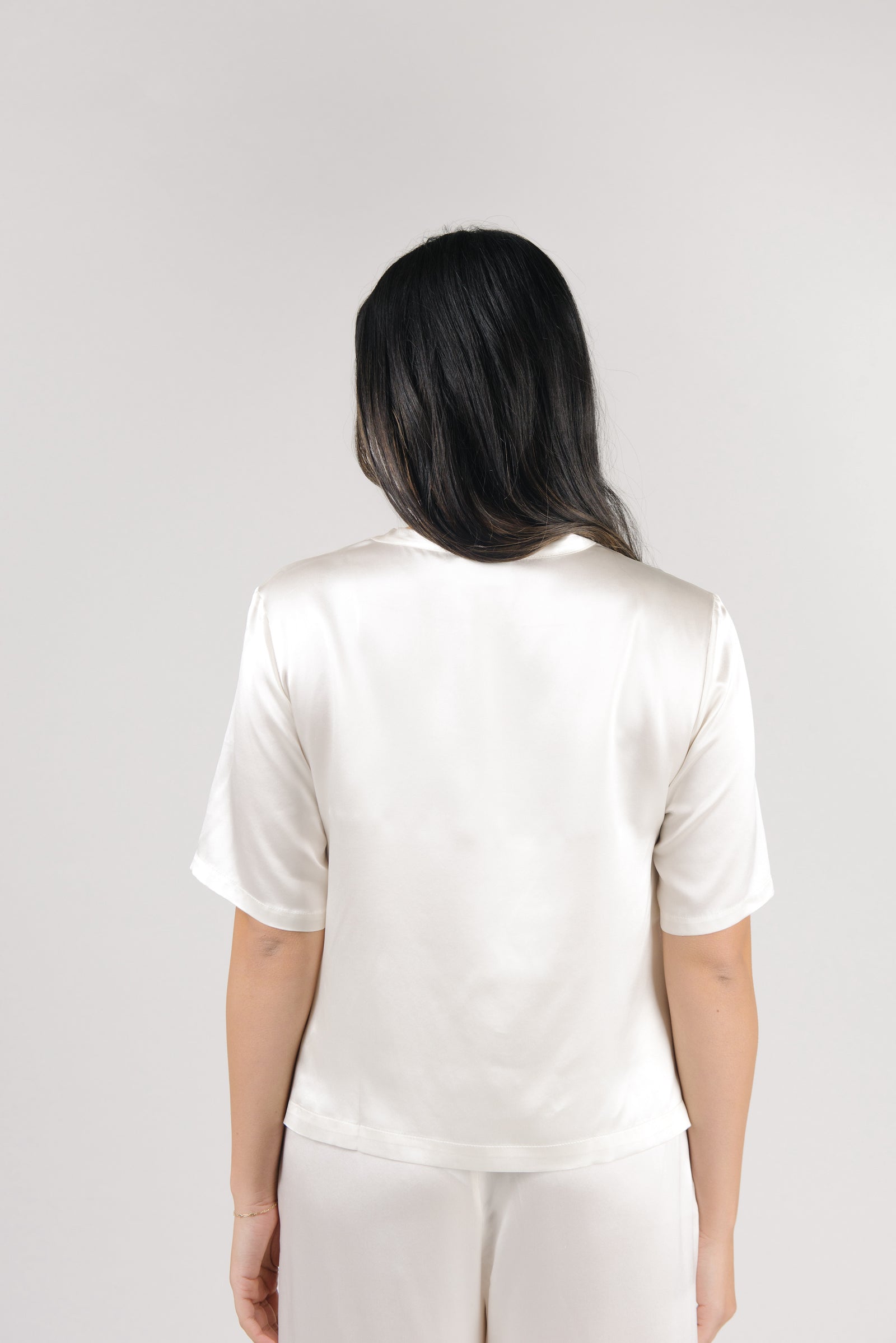 Ivory Serenity Silk Scoop Neck Tee modeled by a woman. The photo was taken in a high contrast setting, showing off the colors and lines of the tee.