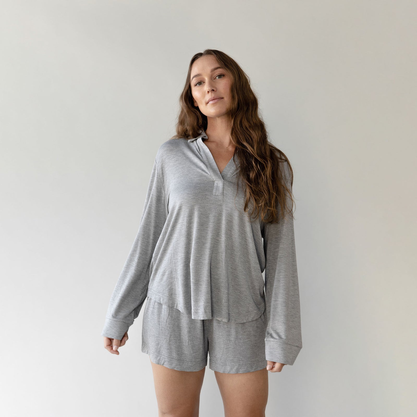 Woman wearing a grey Cozy Earth Bamboo Stretch Knit Long Sleeve Polo and shorts on a plain background