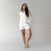 Woman wearing a white Cozy Earth Bamboo Stretch Knit Long Sleeve Polo and shorts on a plain background |Color:Ivory