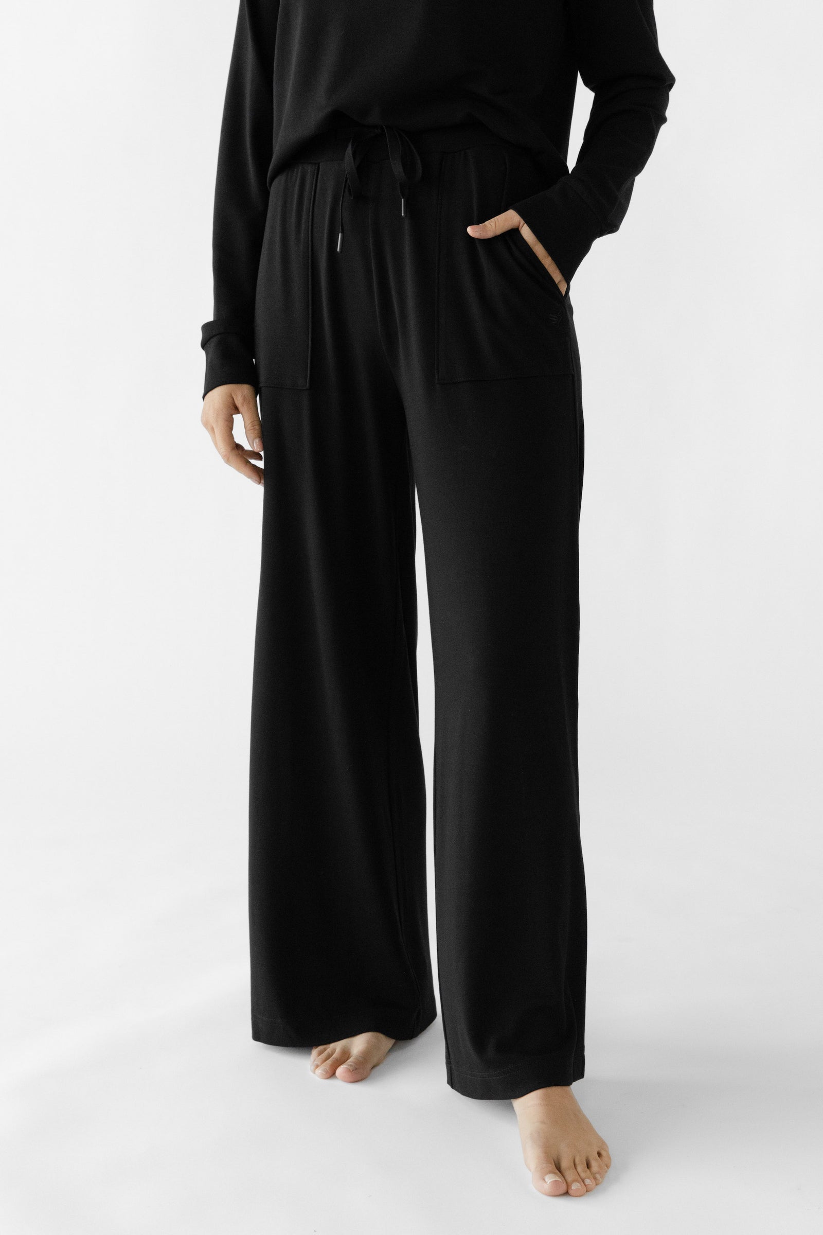 Black Bamboo Wide Leg Patch Pocket Pant modeled by a woman. The photo was taken in a high contrast setting, showing off the colors and lines of the pajamas.