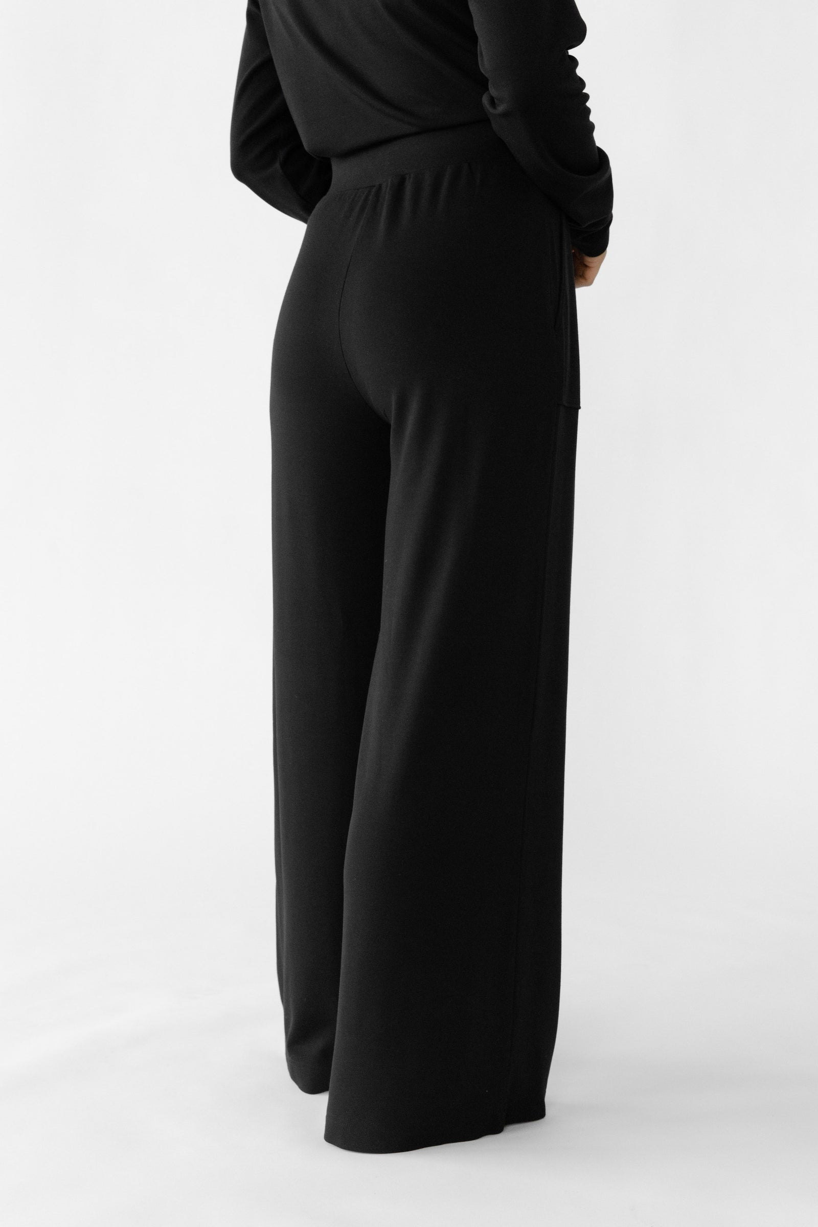 Black Bamboo Wide Leg Patch Pocket Pant modeled by a woman. The photo was taken in a high contrast setting, showing off the colors and lines of the pajamas.