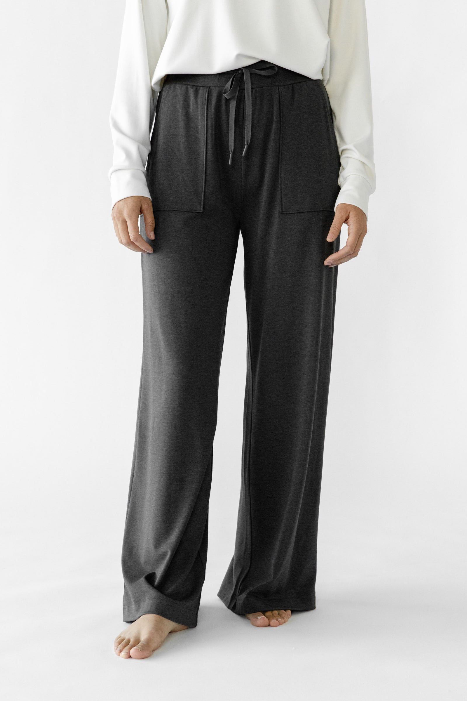Charcoal Bamboo Wide Leg Patch Pocket Pant modeled by a woman. The photo was taken in a high contrast setting, showing off the colors and lines of the pajamas.