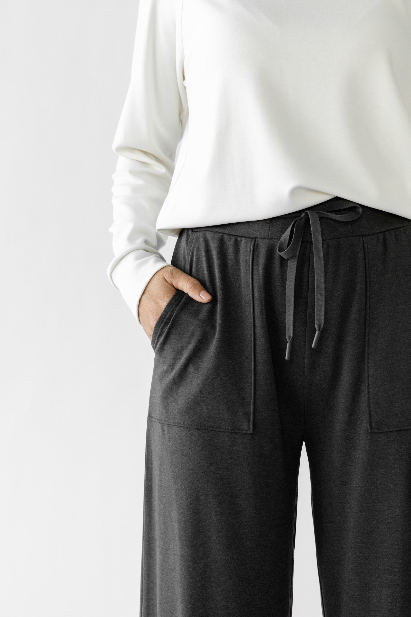 Charcoal Bamboo Wide Leg Patch Pocket Pant modeled by a woman. The photo was taken in a high contrast setting, showing off the colors and lines of the pajamas.