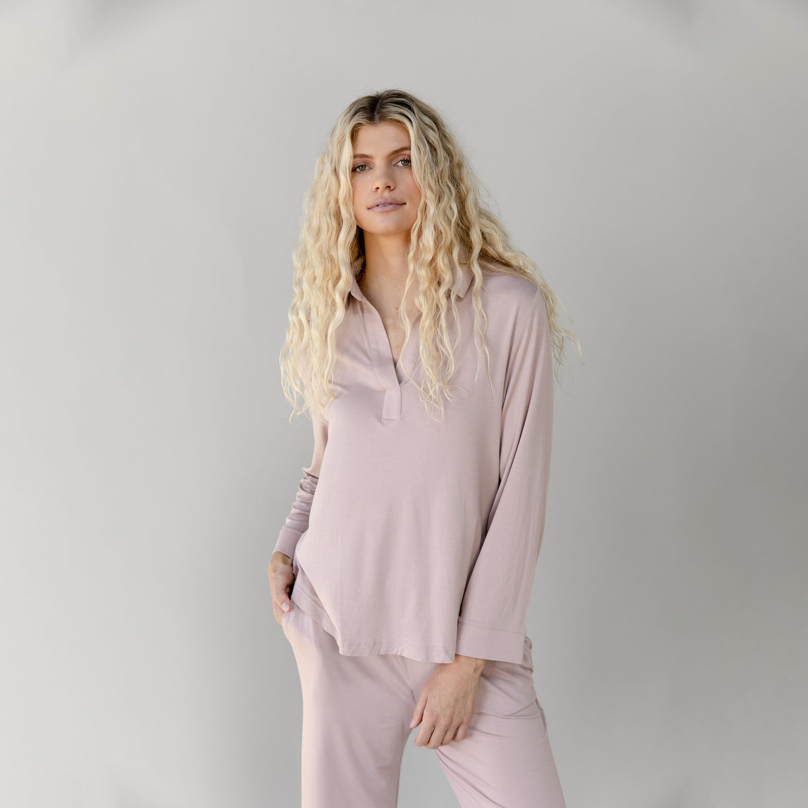 Woman wearing a light pink Cozy Earth Bamboo Stretch Knit Long Sleeve Polo and pants on a plain background