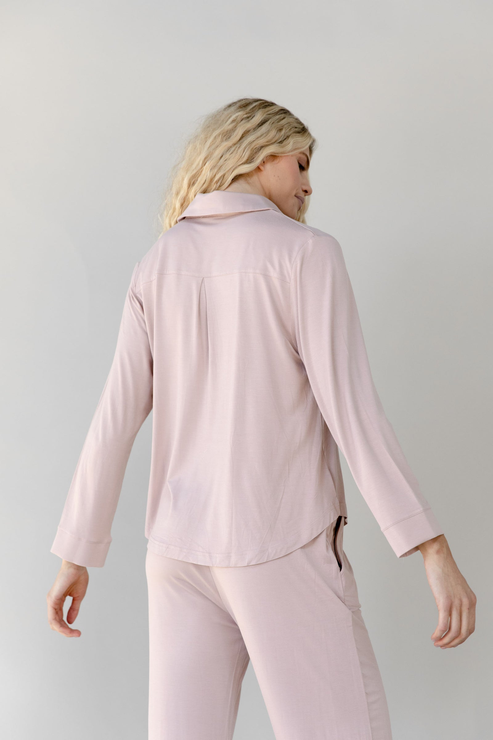 Woman wearing a light pink Cozy Earth Bamboo Stretch Knit Long Sleeve Polo and pants on a plain background
