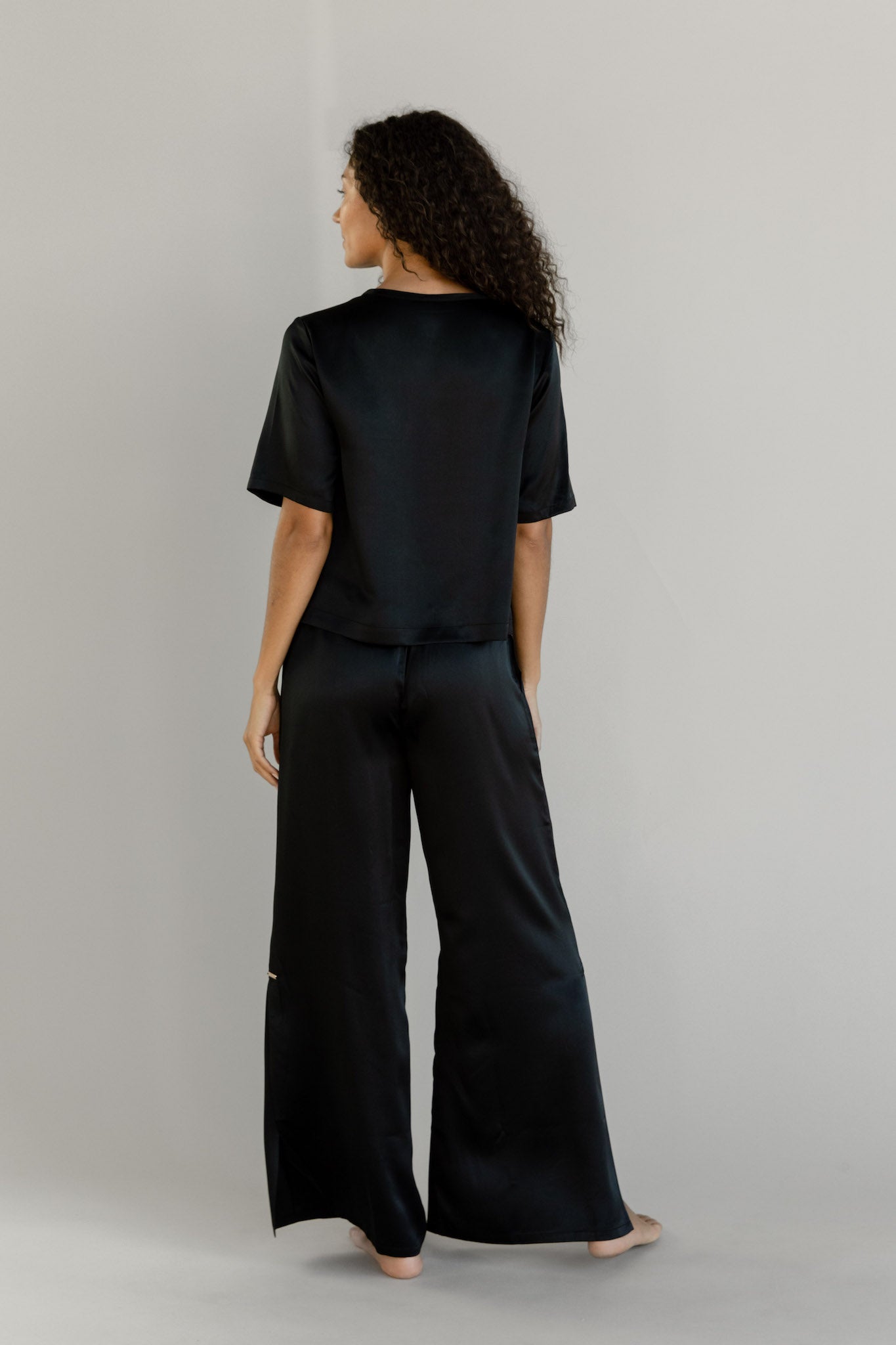 Black Serenity Silk Scoop Neck Tee modeled by a woman. The photo was taken in a high contrast setting, showing off the colors and lines of the tee.