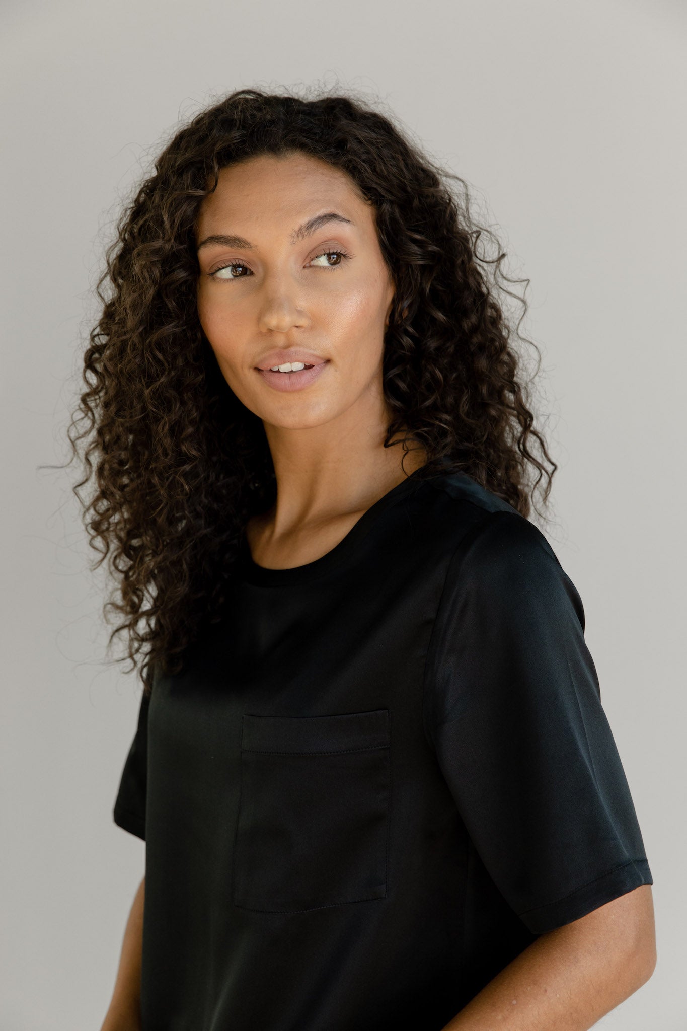 Black Serenity Silk Scoop Neck Tee modeled by a woman. The photo was taken in a high contrast setting, showing off the colors and lines of the tee.