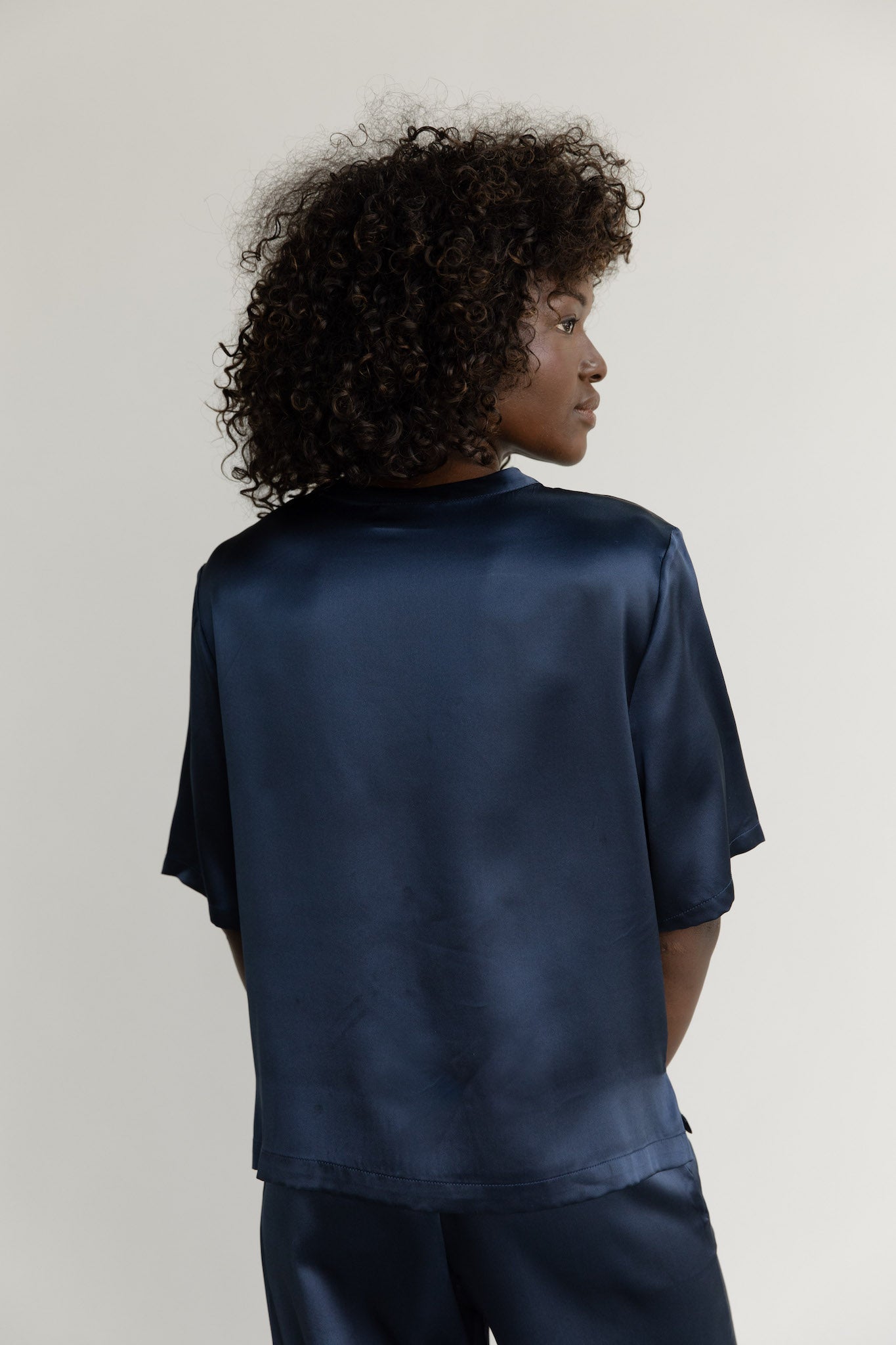 Navy Serenity Silk Scoop Neck Tee modeled by a woman. The photo was taken in a high contrast setting, showing off the colors and lines of the tee.