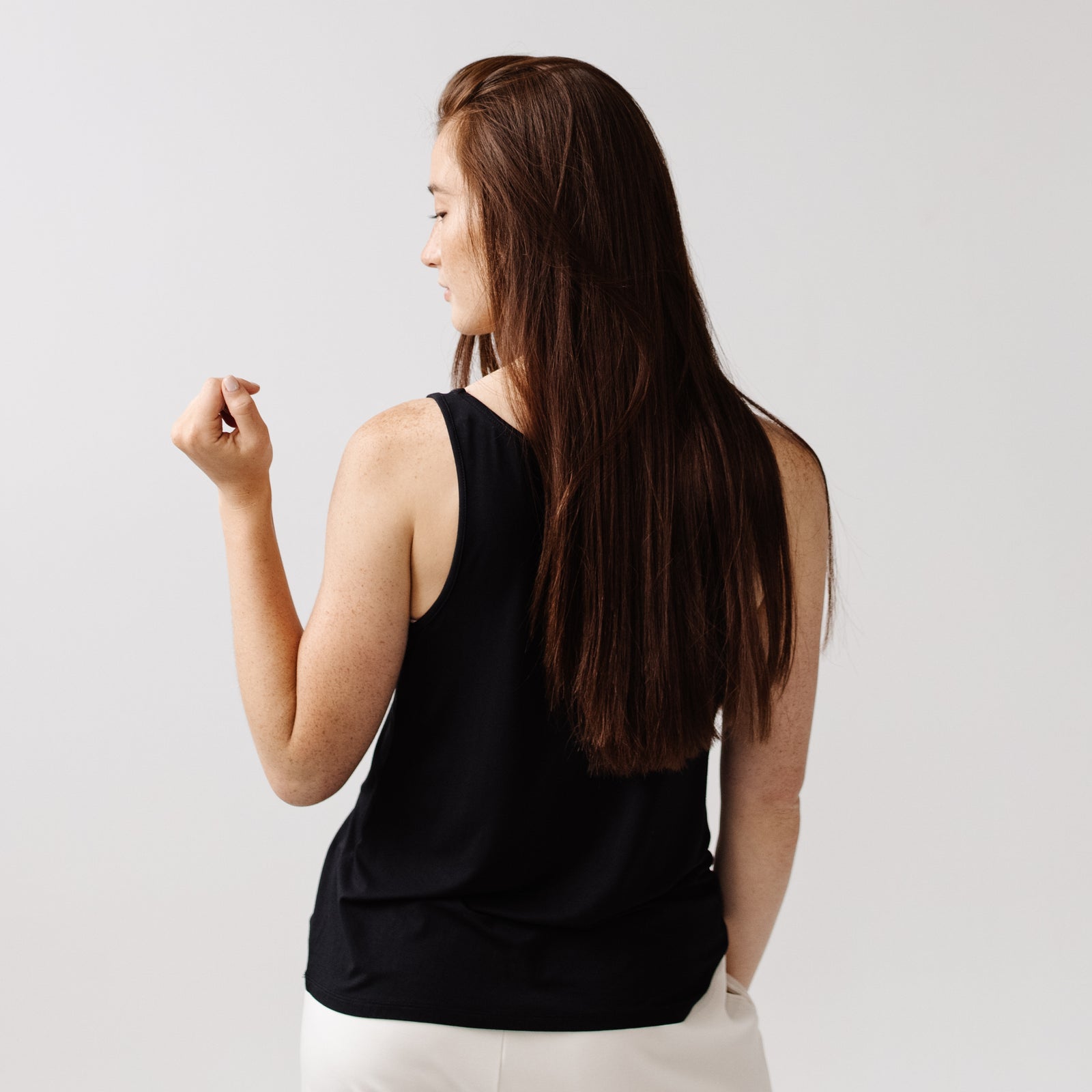A woman facing backwards wears a black Cozy Earth Stretch Knit Tank