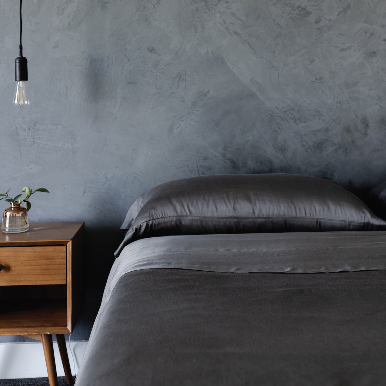 Dark bedroom with a bed with charcoal bedding