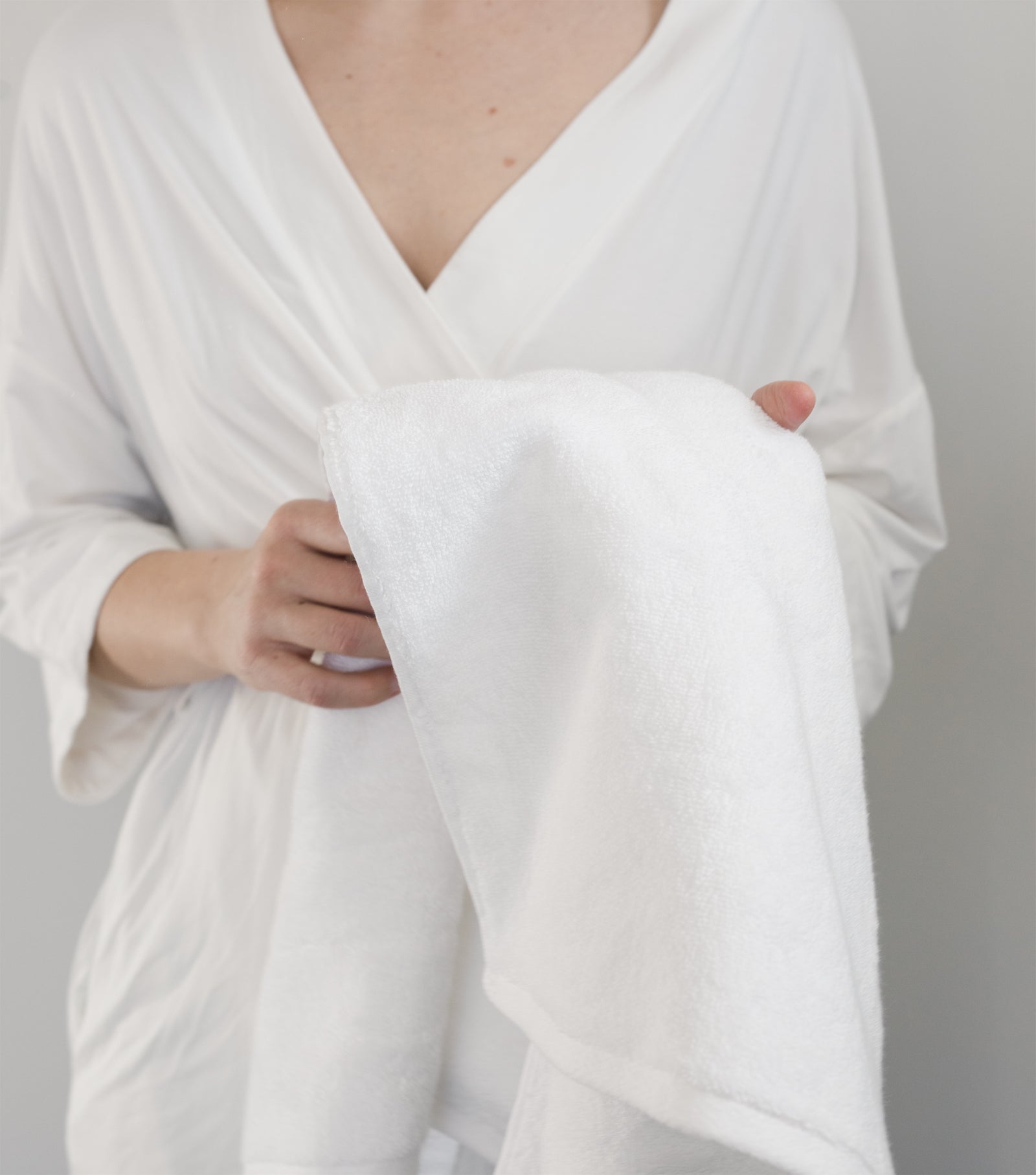 Premium Plush Bath Towel in the color White. Photo of White Premium Plush Bath Towel taken with women wrapped in the premium plush bath towel. The photo is shot from the neck to the torso. 