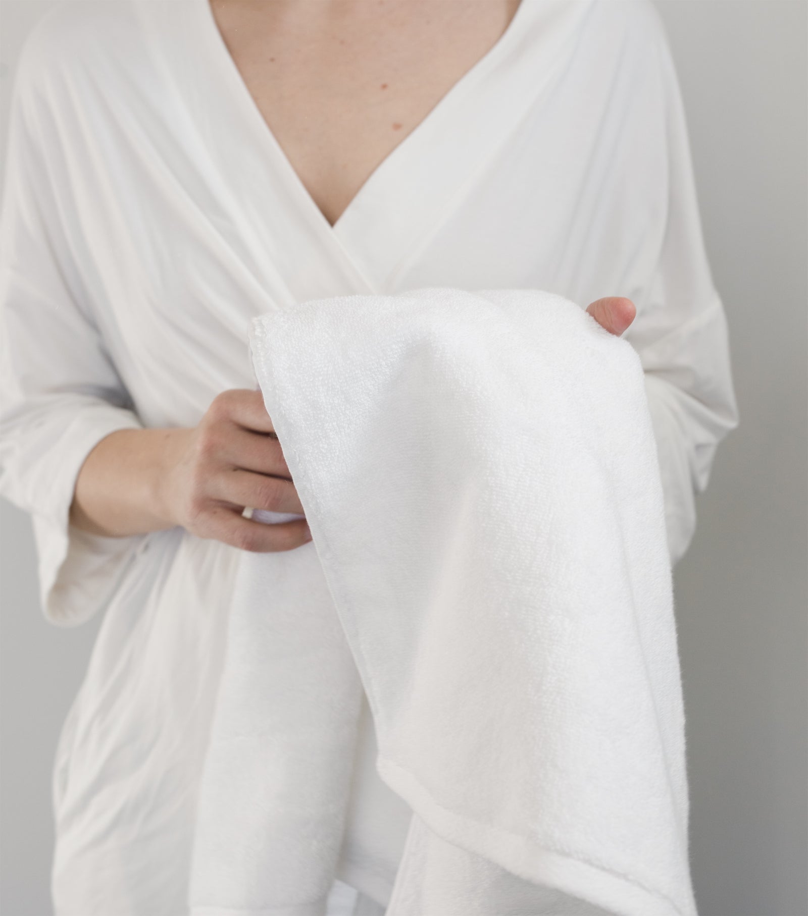 Premium Plush Bath Towel in the color White. Photo of White Premium Plush Bath Towel taken with women wrapped in the premium plush bath towel. The photo is shot from the neck to the torso.