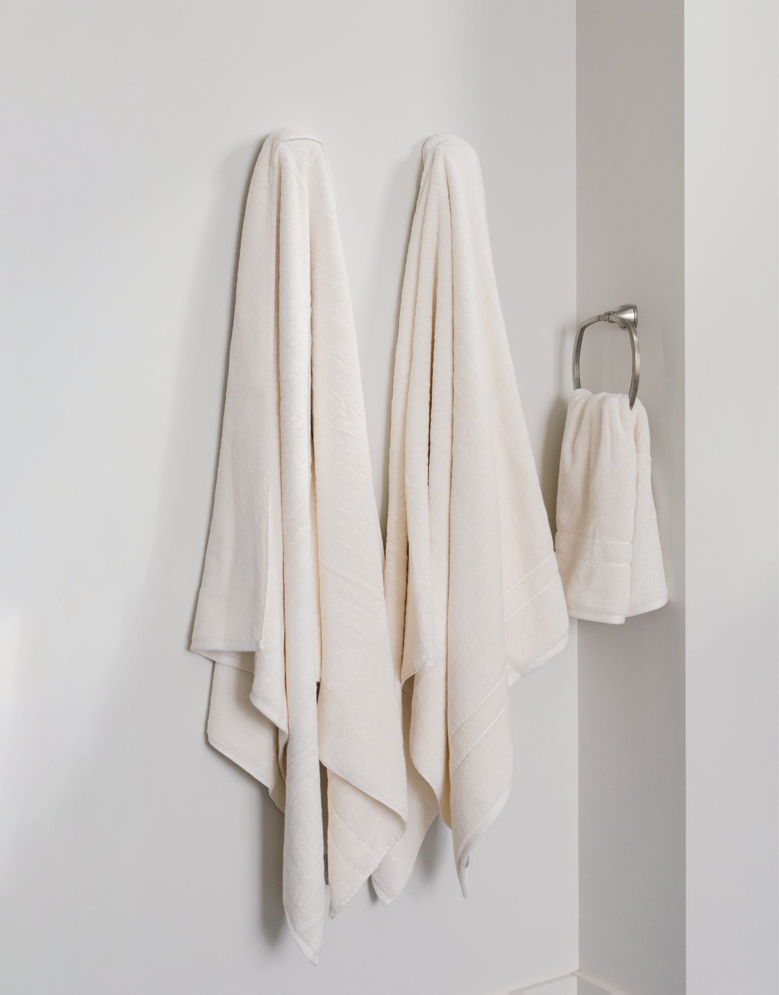 Premium Plush Bath Towels in the color Creme. Photo of Premium Plush Bath Towels taken in a bathroom showing the towels which are hung from a towel rack.