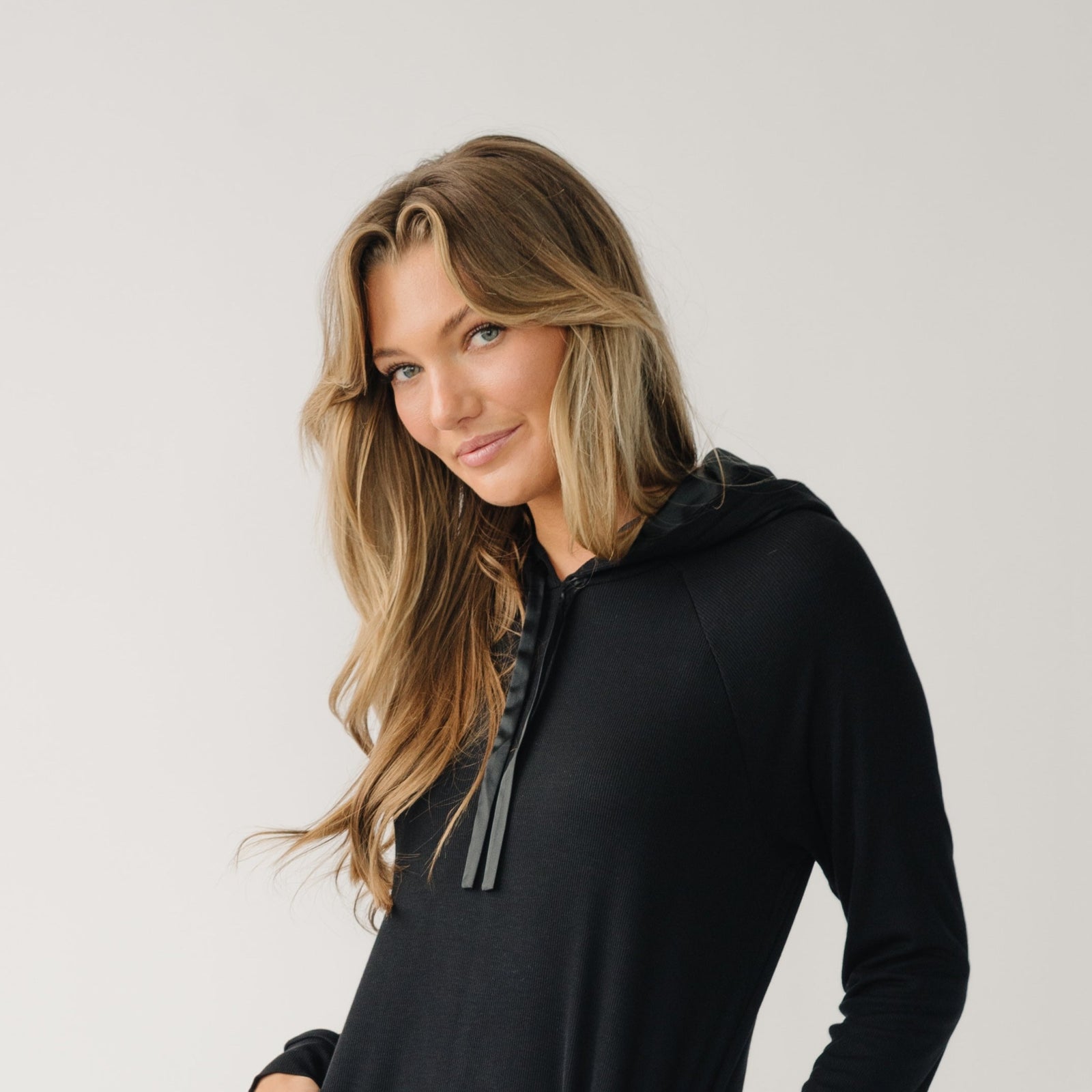 Woman wearing a Cozy Earth Rib Knit Hoodie in black against a white background
