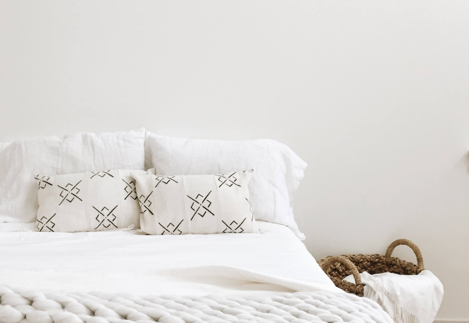 Bed with with bedding and a brown basket to the side