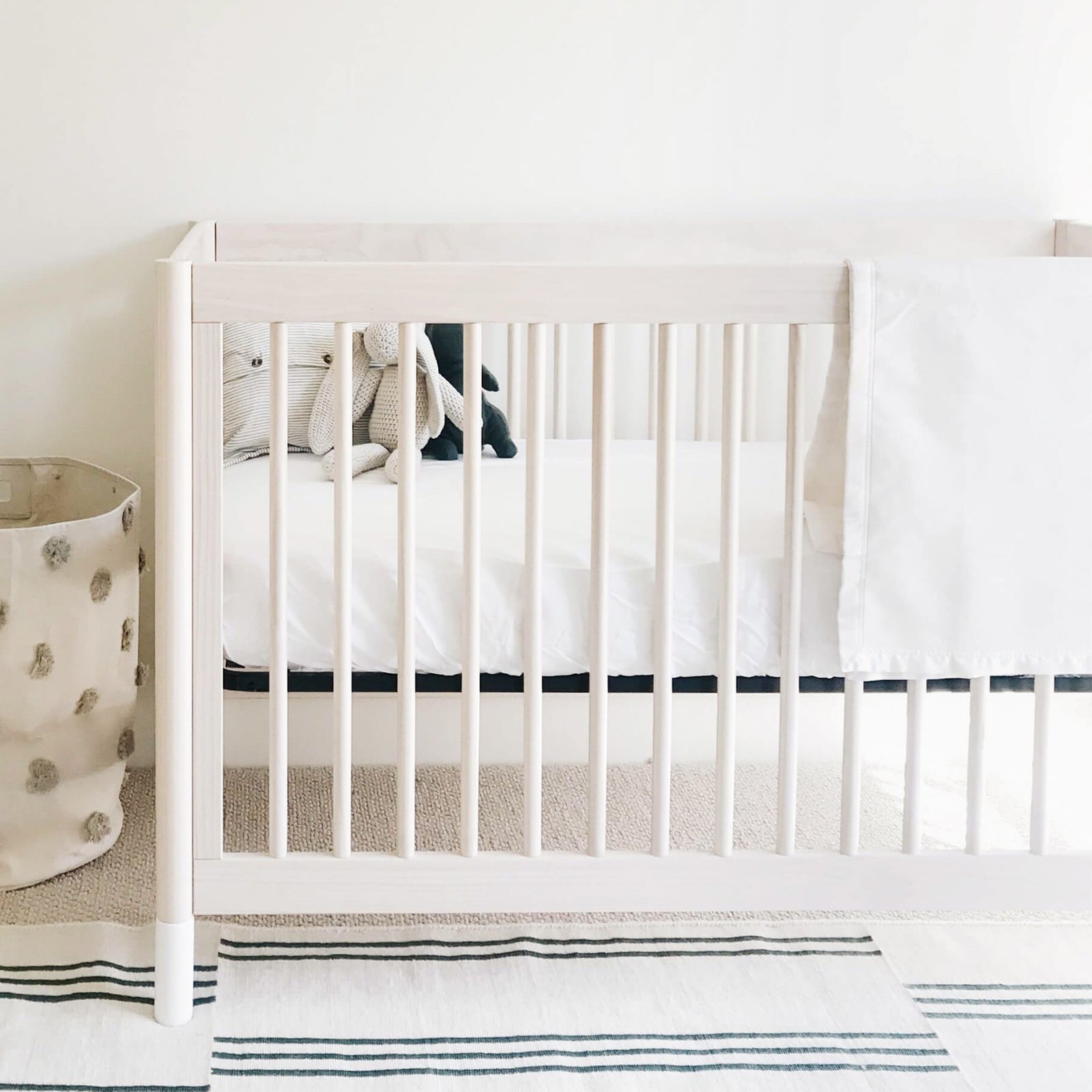 White crib with baby blanket draped over the side