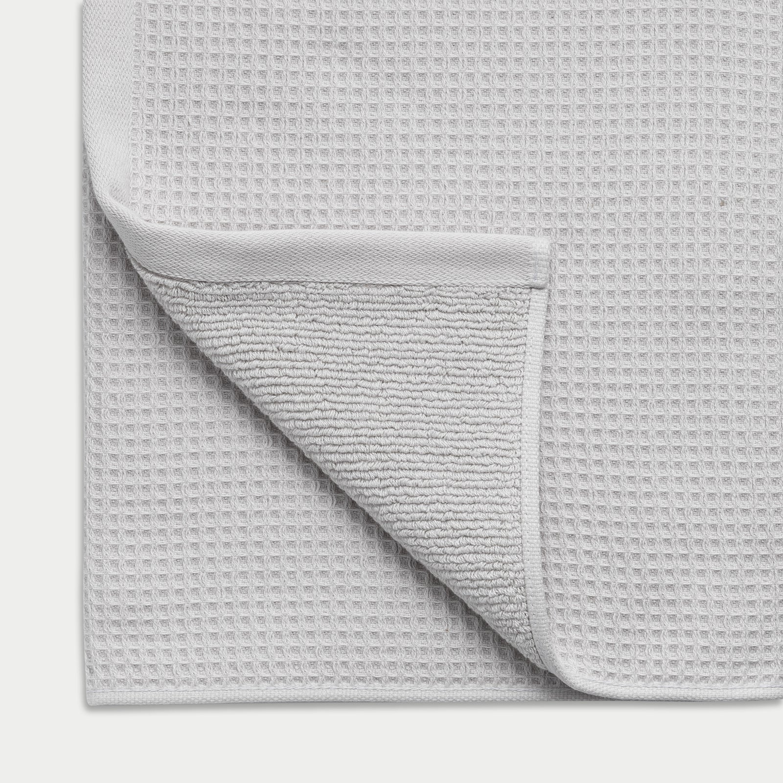 Waffle Bath Towel in the color Light Grey. Photo of Light Grey Waffle Bath Towel taken close up showing the corner of the towel