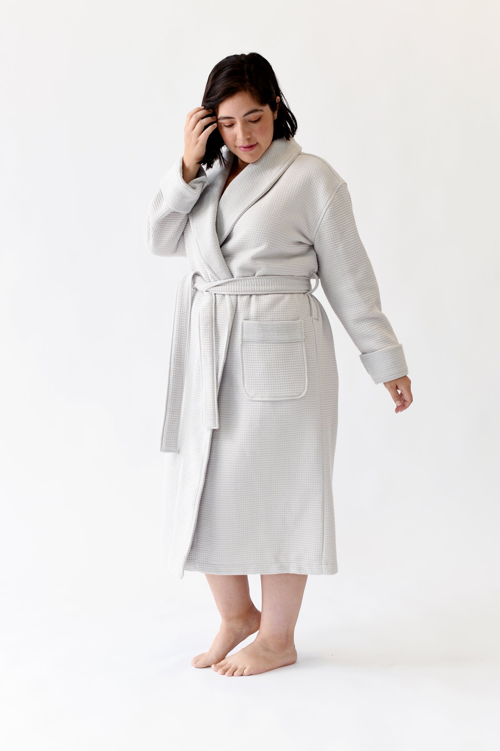 Woman wearing Bamboo Waffle Bath robe standing in front of a with a white background. 