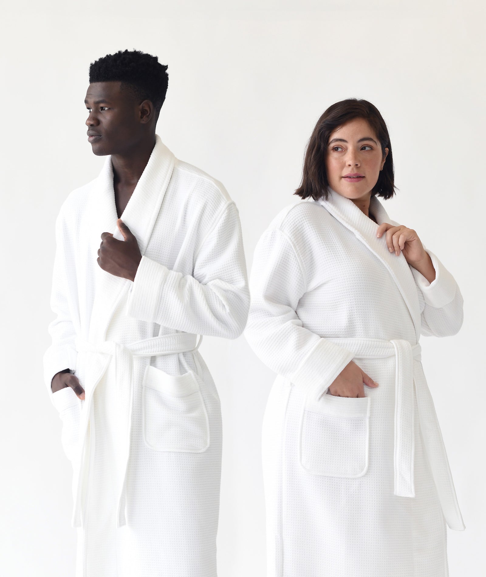  Man and woman standing in front of white background. both the man and the woman are wearing white bamboo waffle knit robes. 