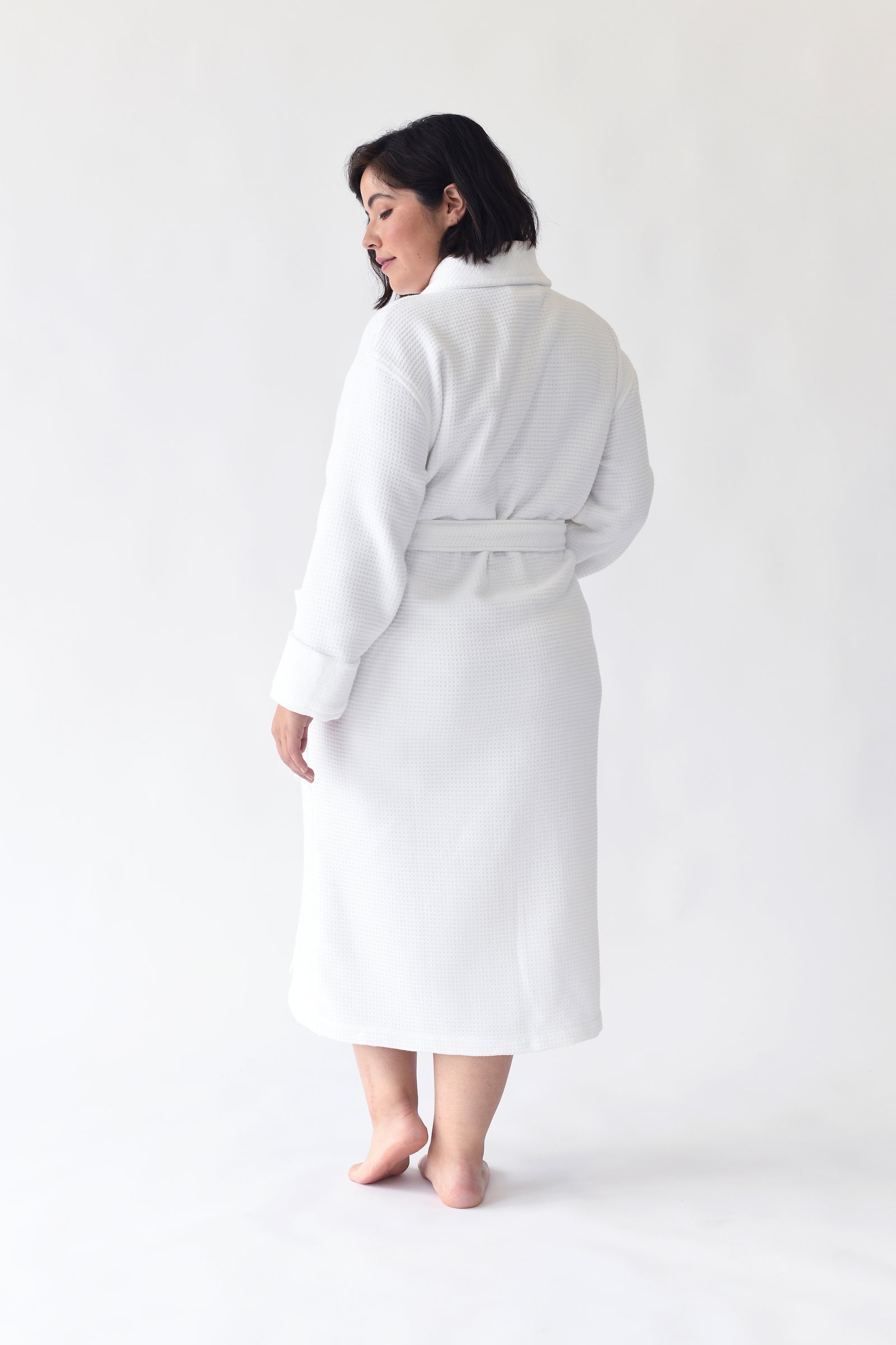 Woman wearing Bamboo Waffle Bath robe standing in front of a with a white background. 