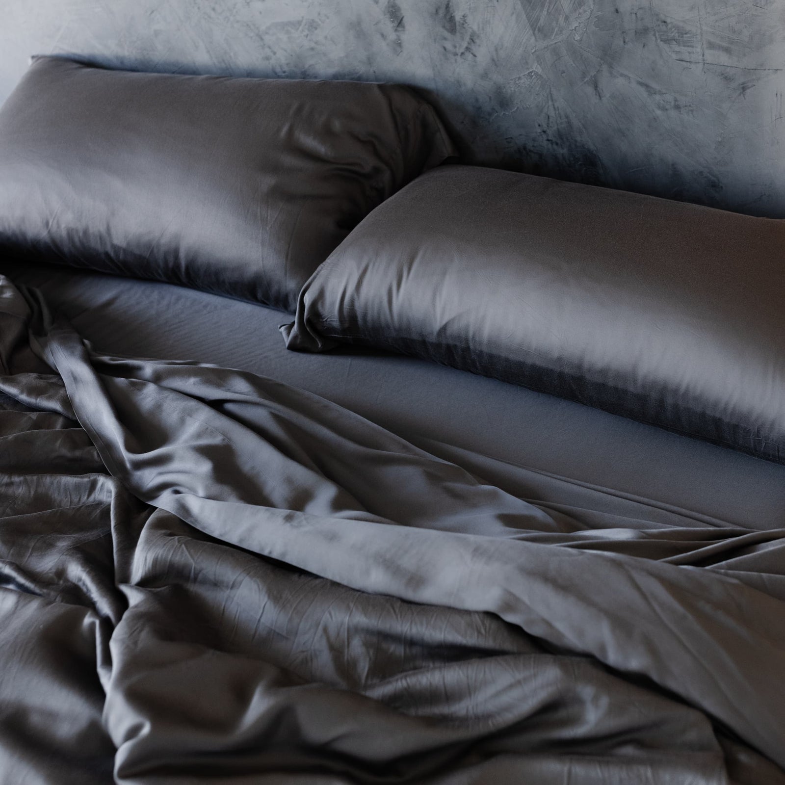 Unmade bed with charcoal bedding 